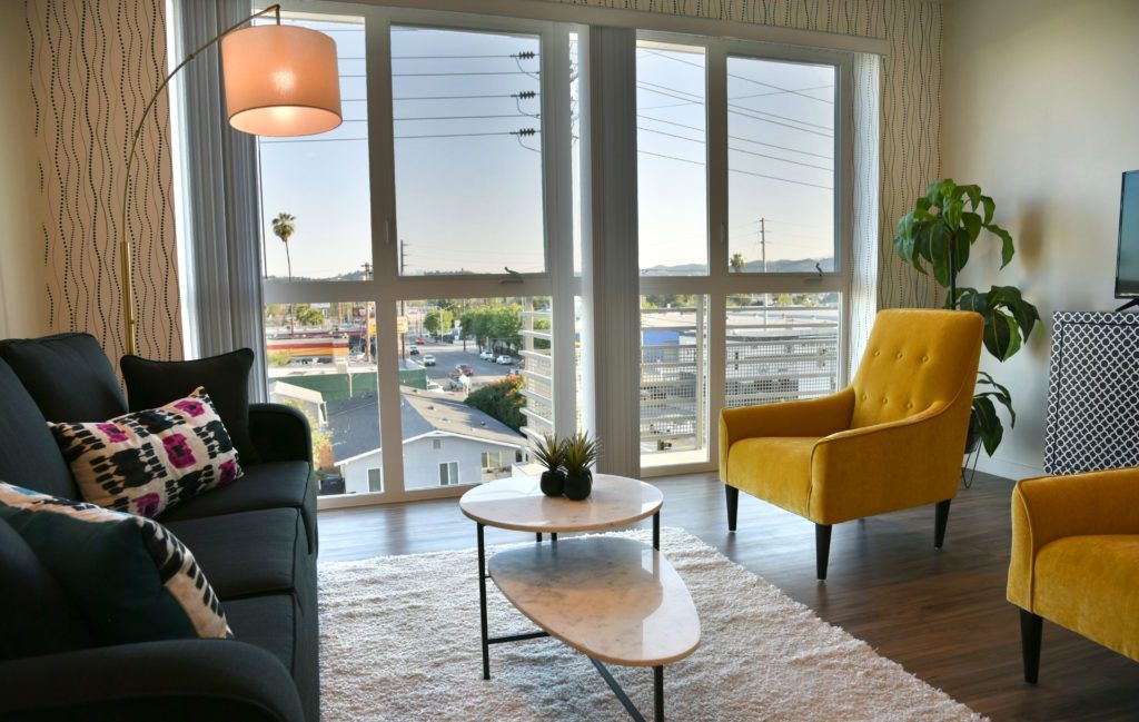 A living room with a couch , chairs , coffee table and large windows.