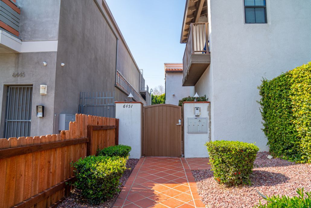 A walkway leading to a building with a wooden fence and a gate.