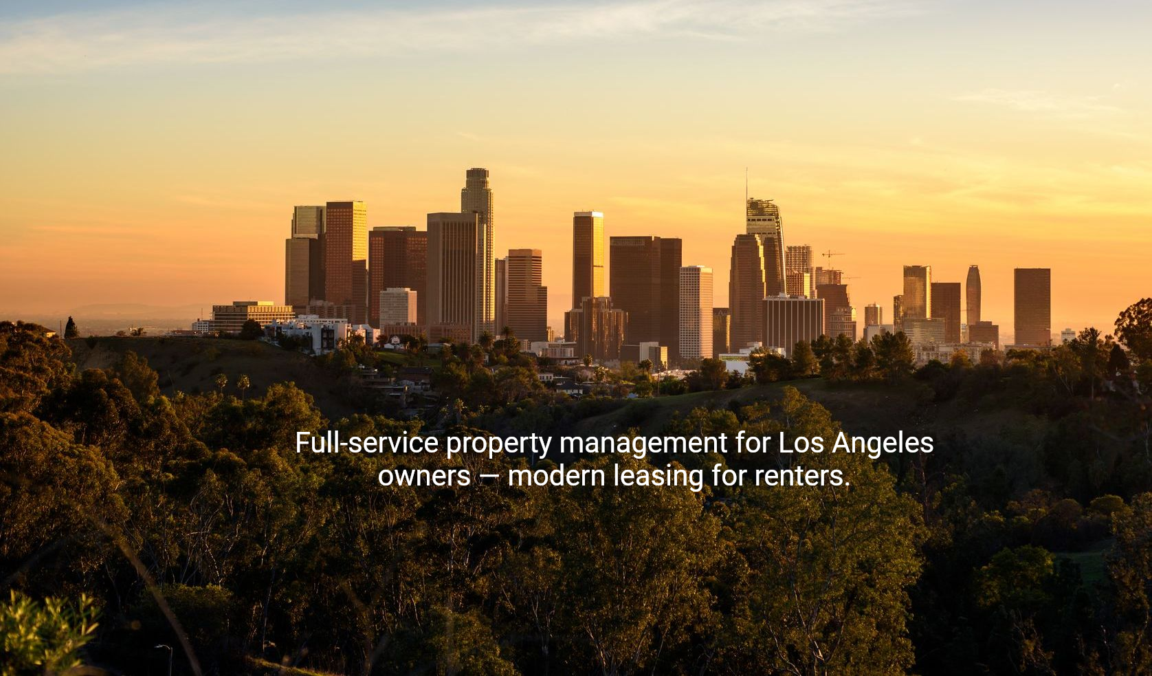 The skyline of los angeles is visible through the trees at sunset.
