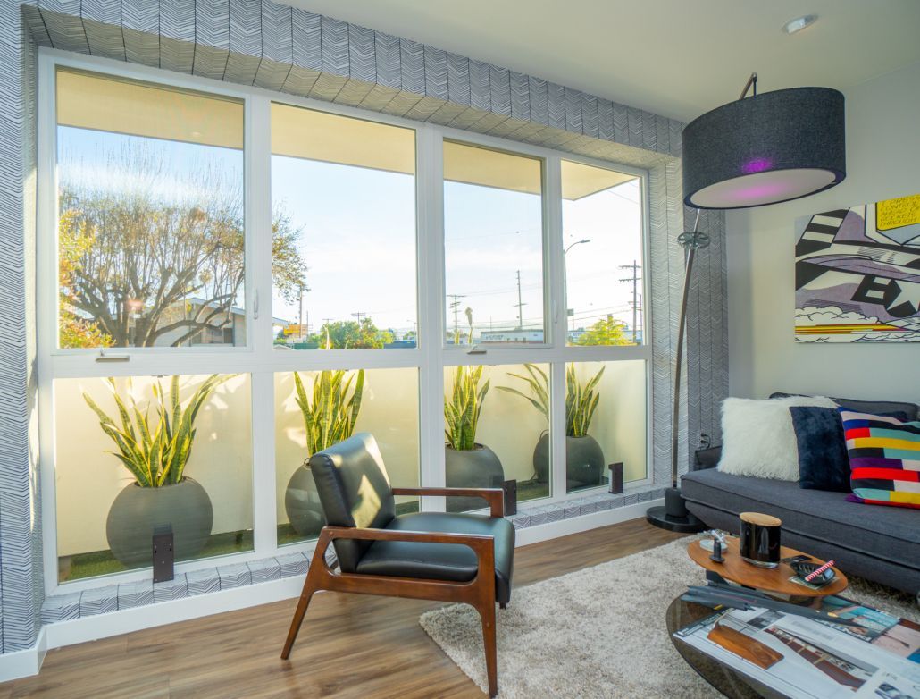 A living room with a couch , chair , coffee table and lots of windows.