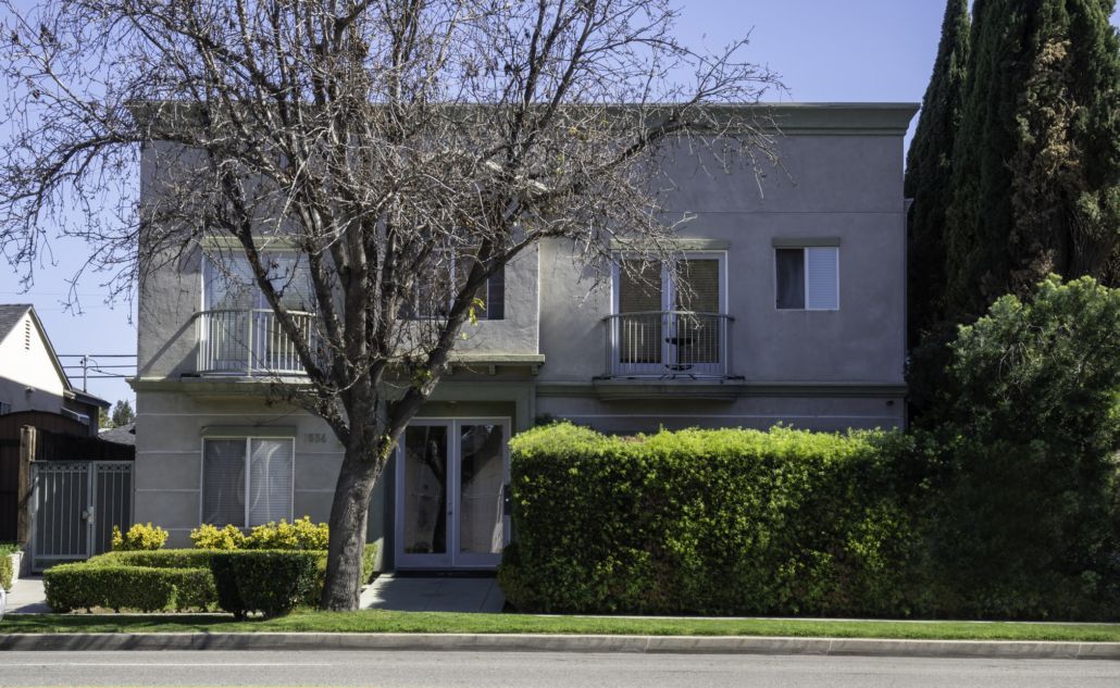 A large apartment building with a tree in front of it.