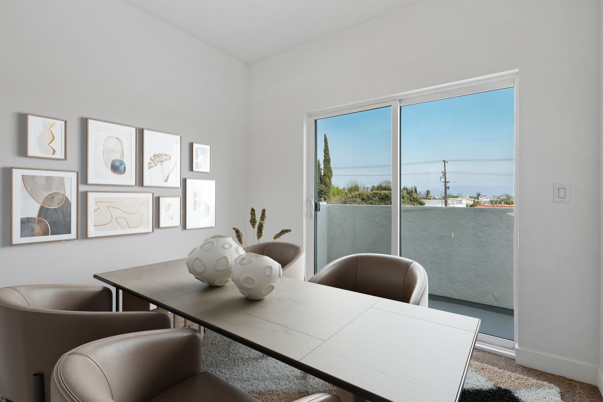 A dining room with a table and chairs and a balcony.