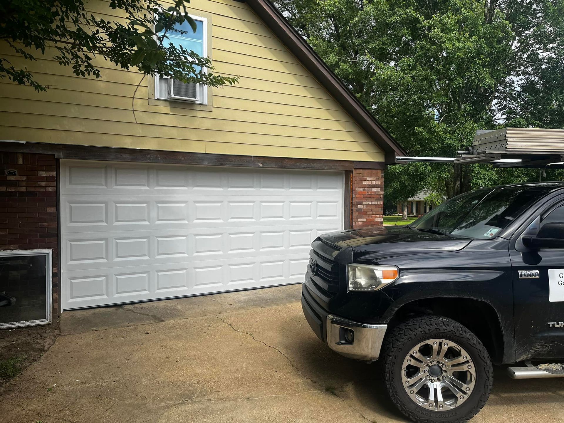 A black truck is parked in front of a garage door.