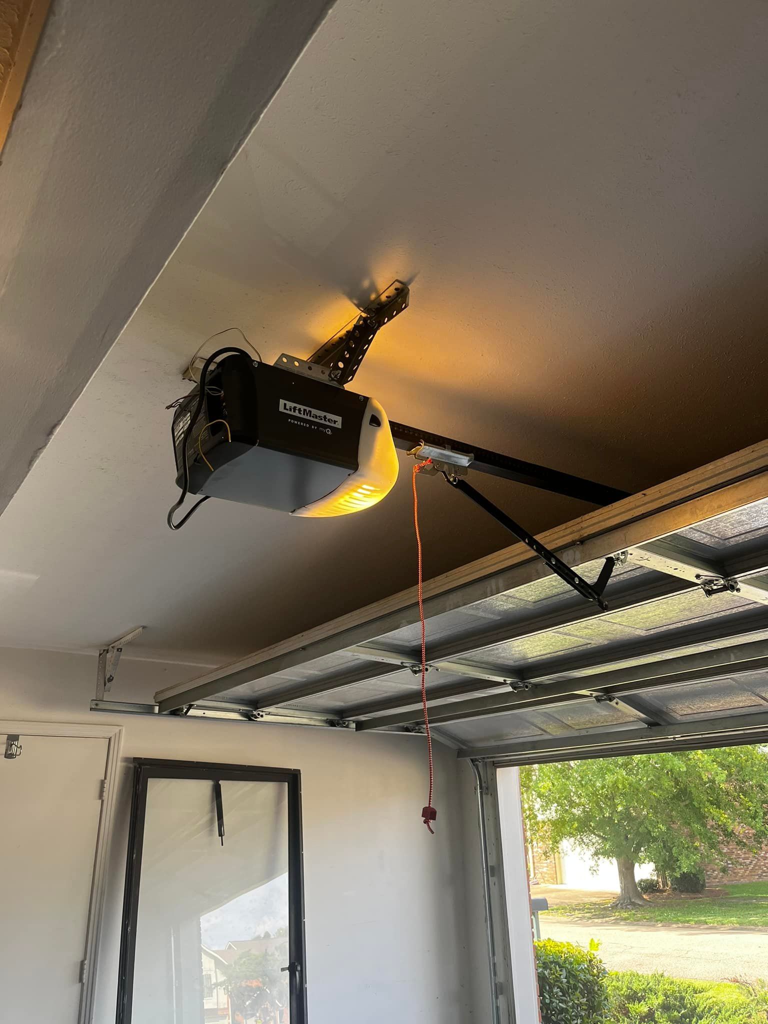 A garage door opener is hanging from the ceiling of a garage.