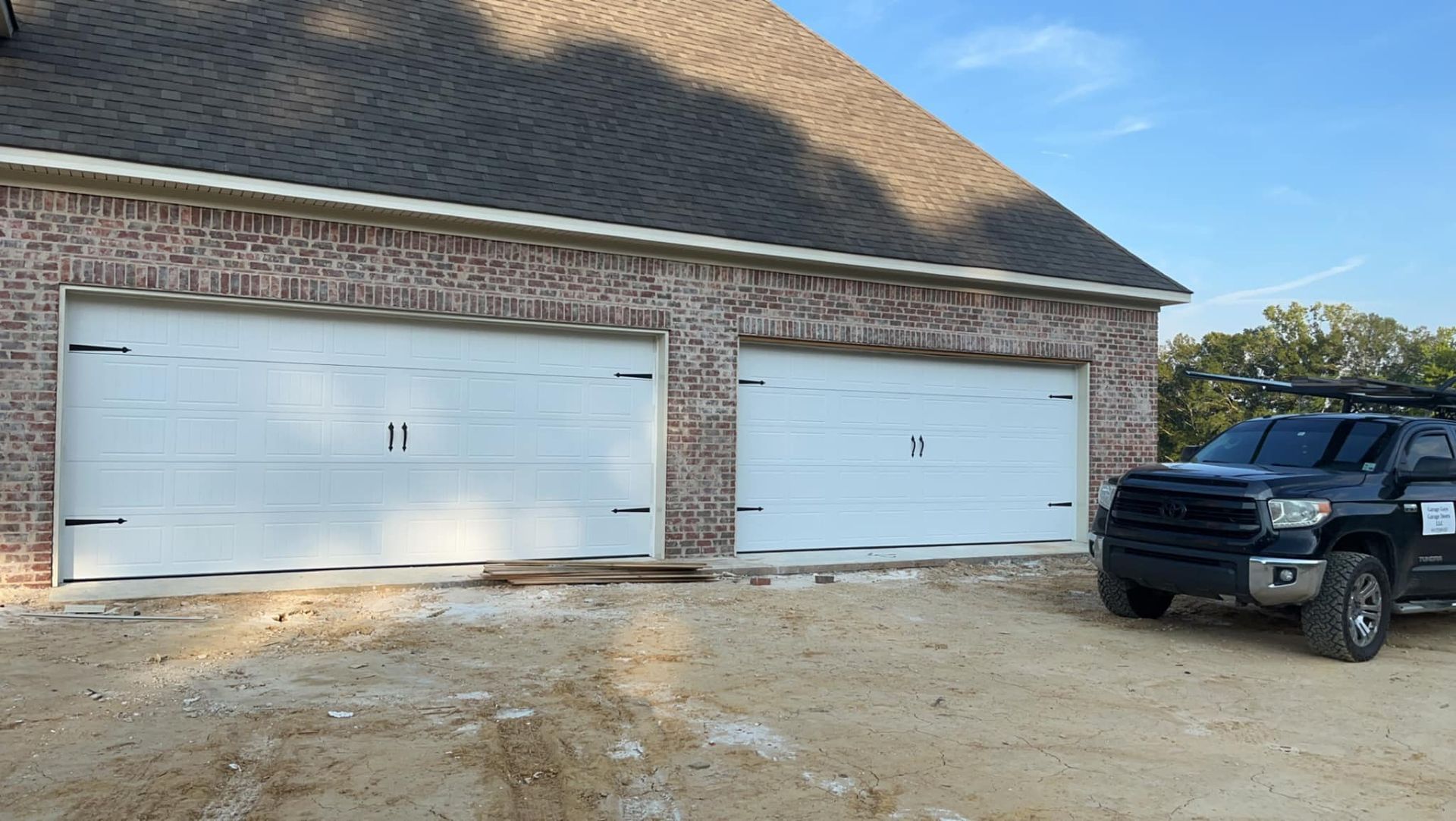A black truck is parked in front of a garage door.