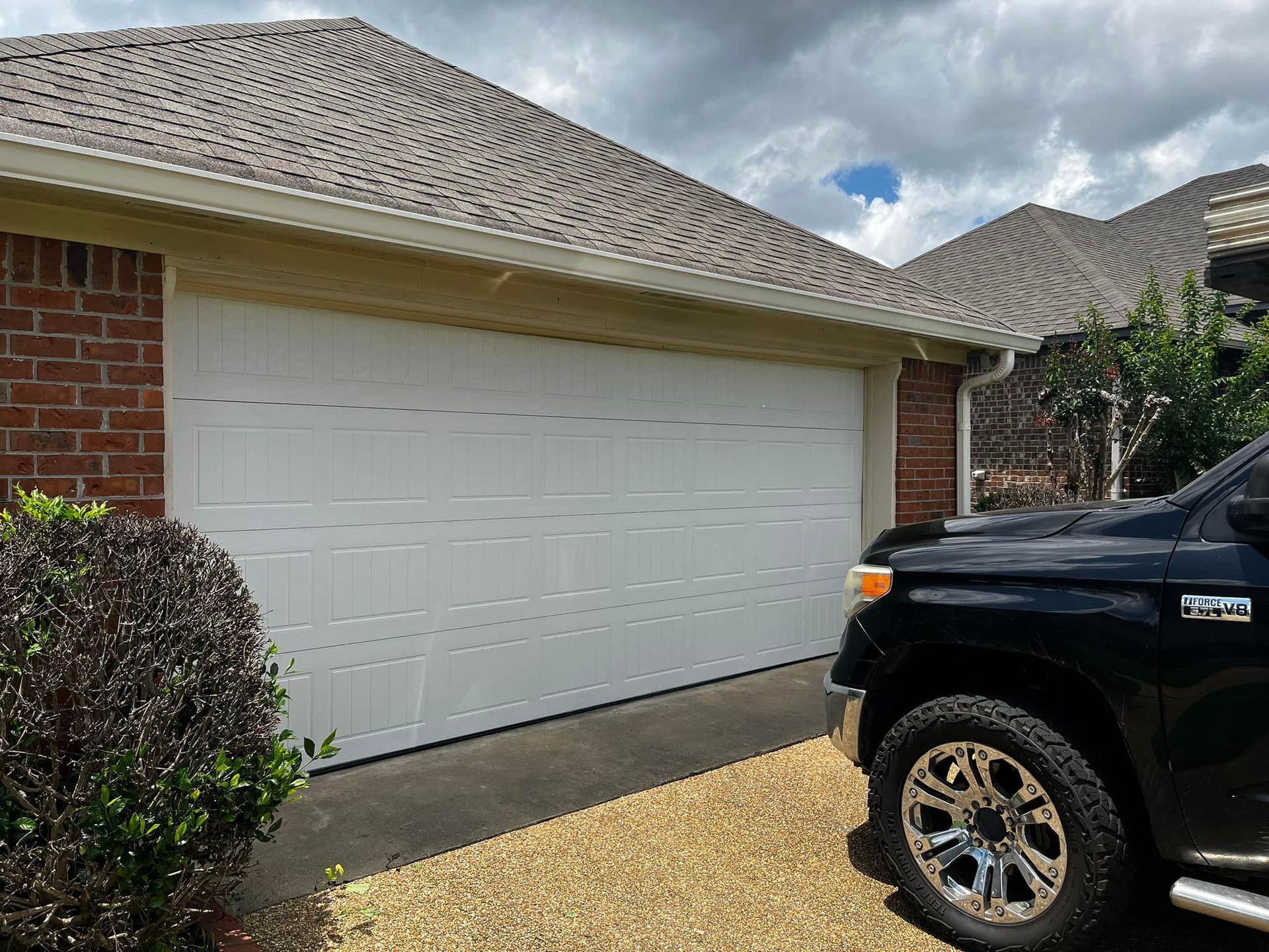 A black truck is parked in front of a white garage door.