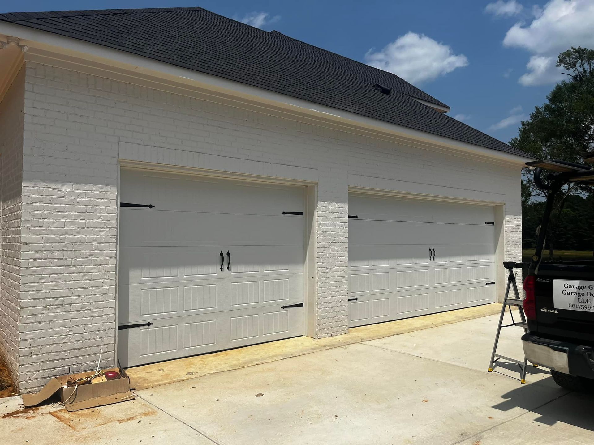 A truck is parked in front of a white garage door.