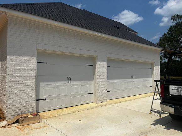 A truck is parked in front of a white garage door.