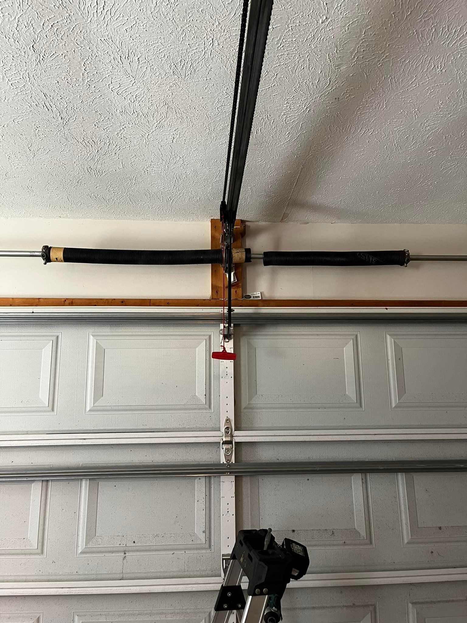 A garage door with a broken spring hanging from the ceiling.