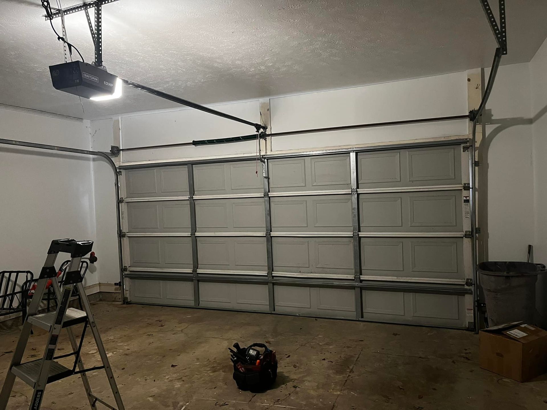 A garage with a garage door open and a ladder.