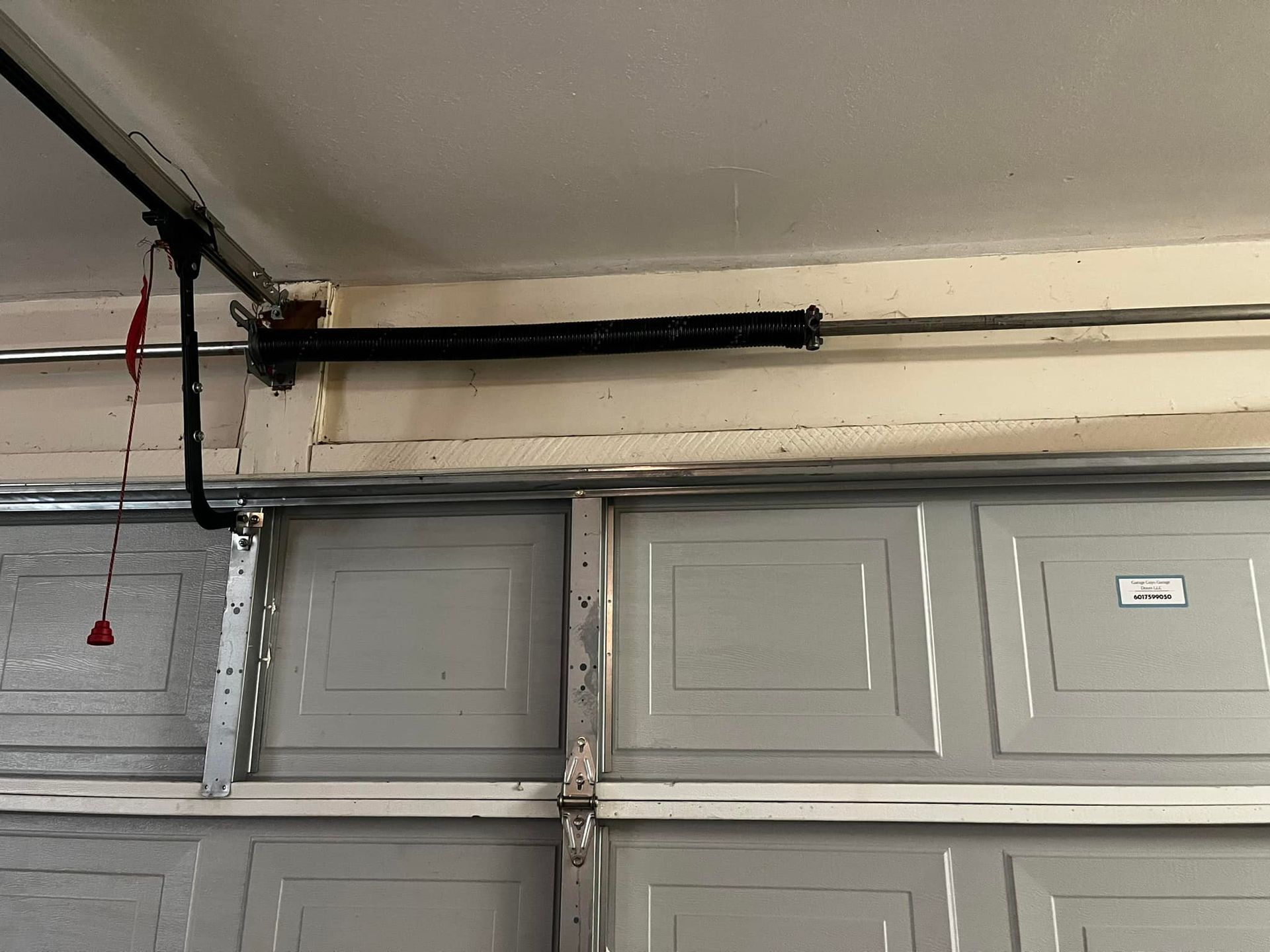 A garage door with a spring hanging from the ceiling.