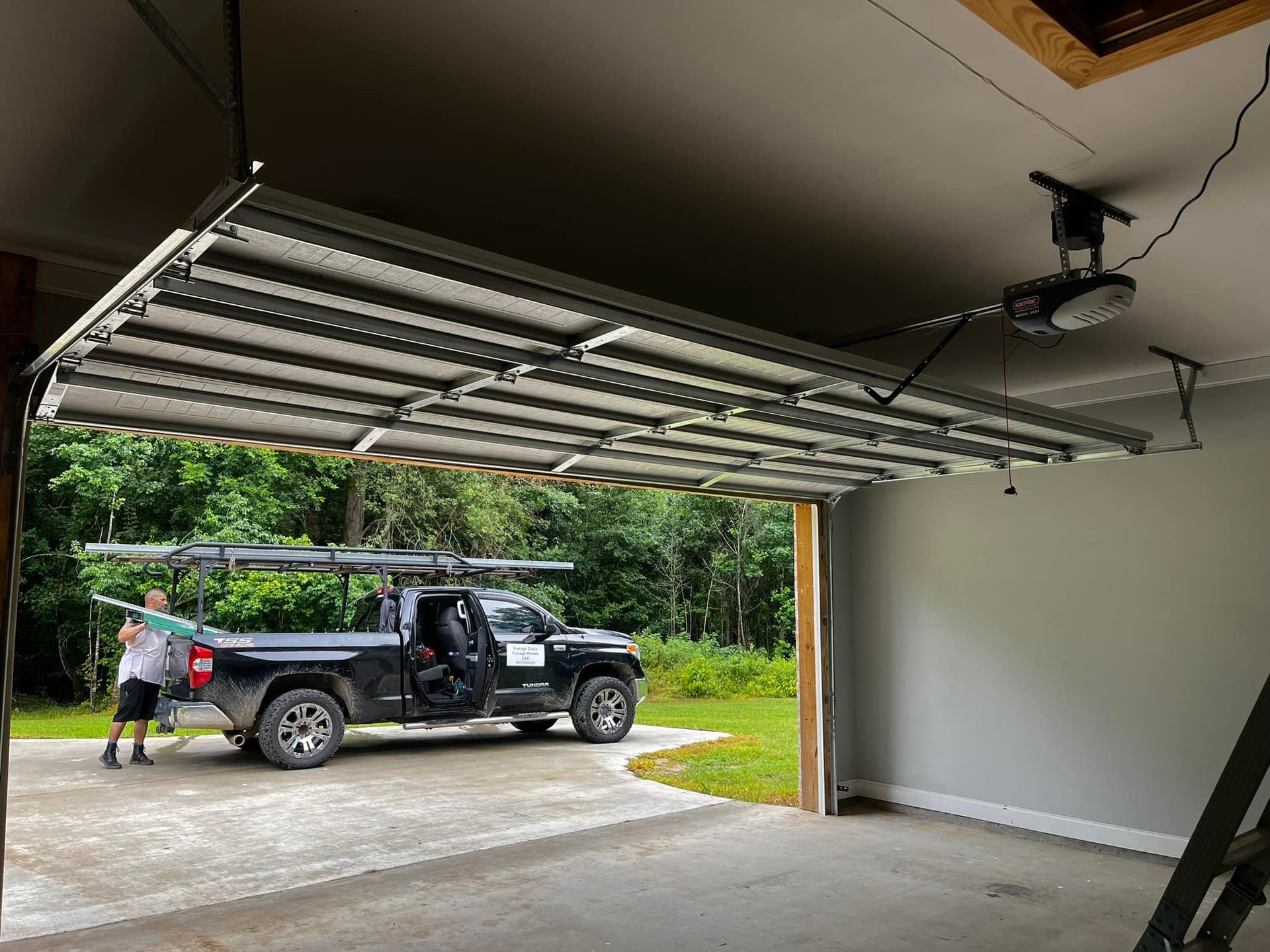 A truck is parked in a garage with the door open.