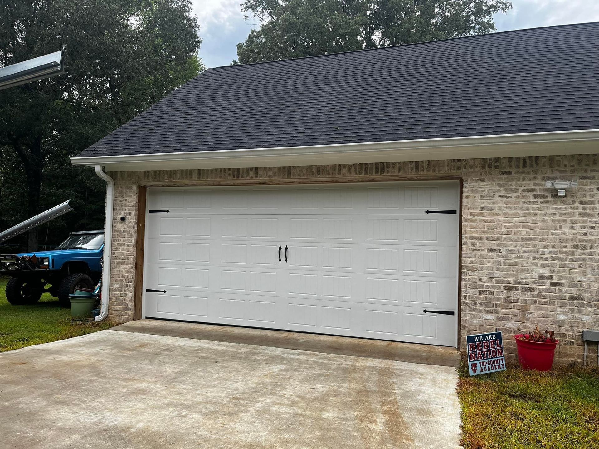 A blue truck is parked in front of a white garage door.
