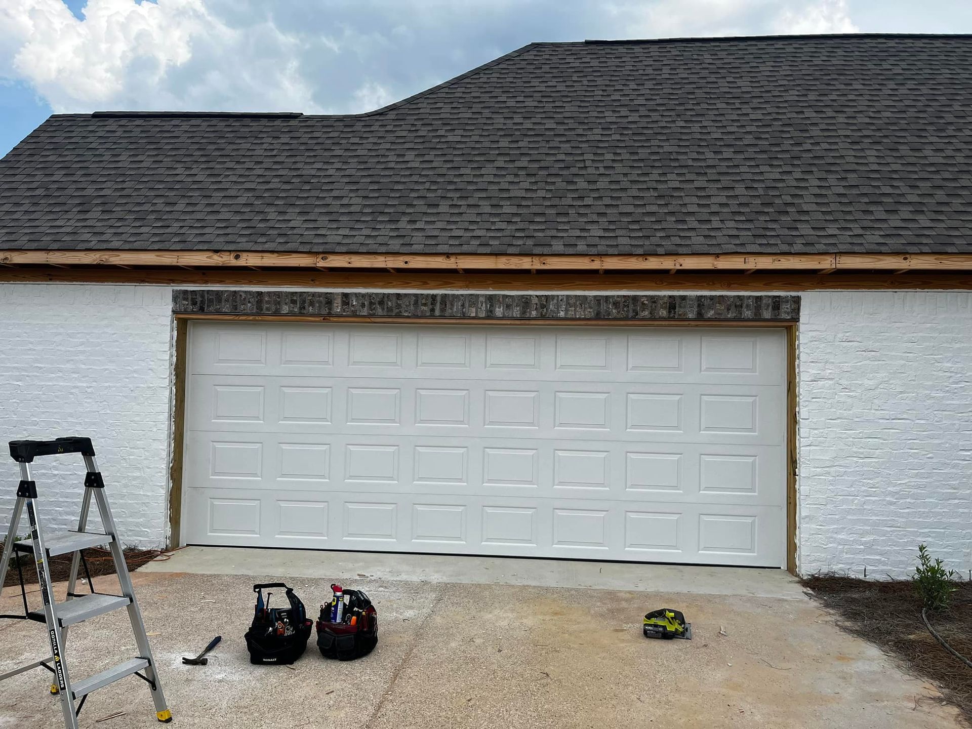 A white garage door is being installed on a house.