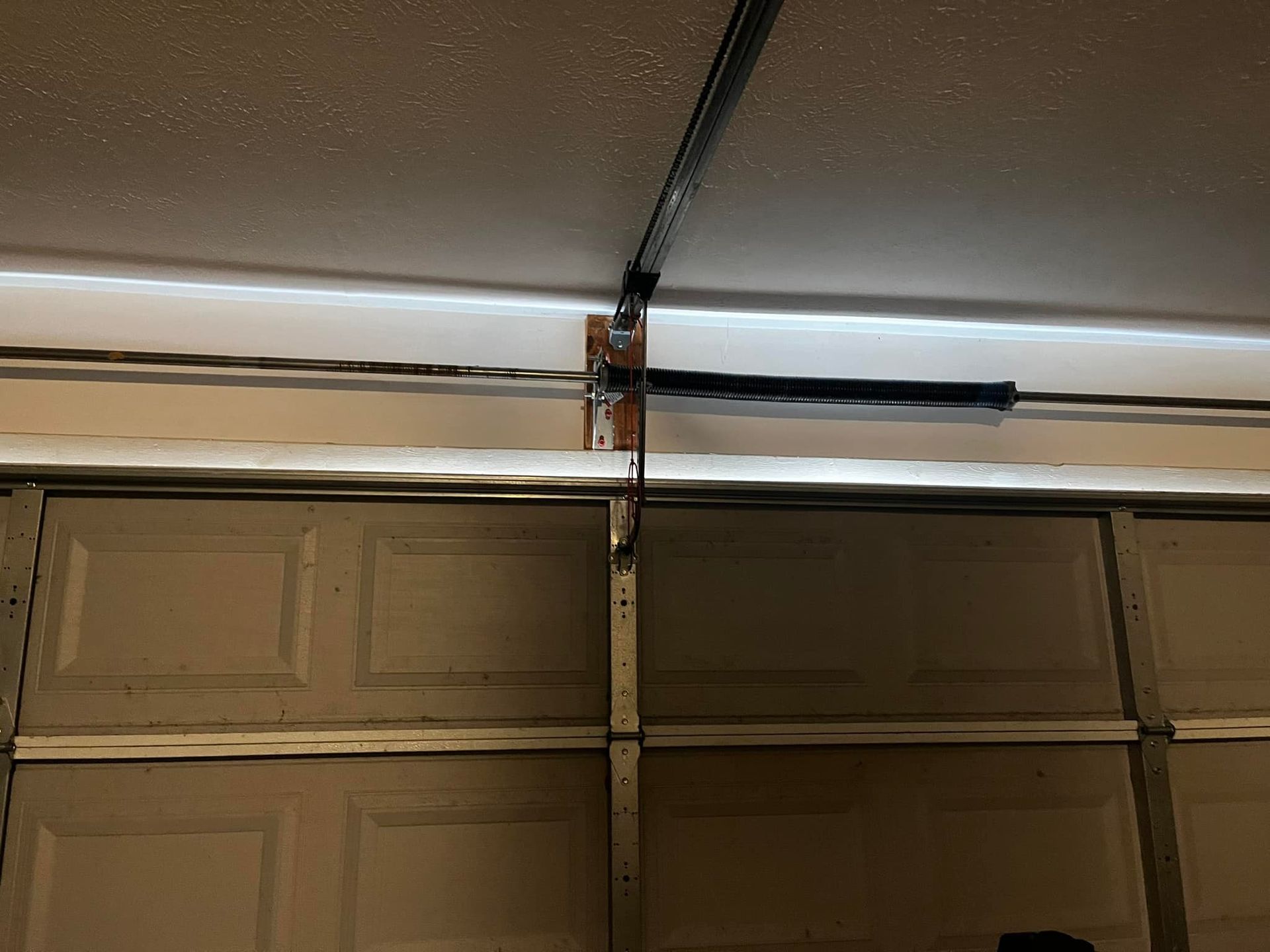 A garage door opener is hanging from the ceiling of a garage.