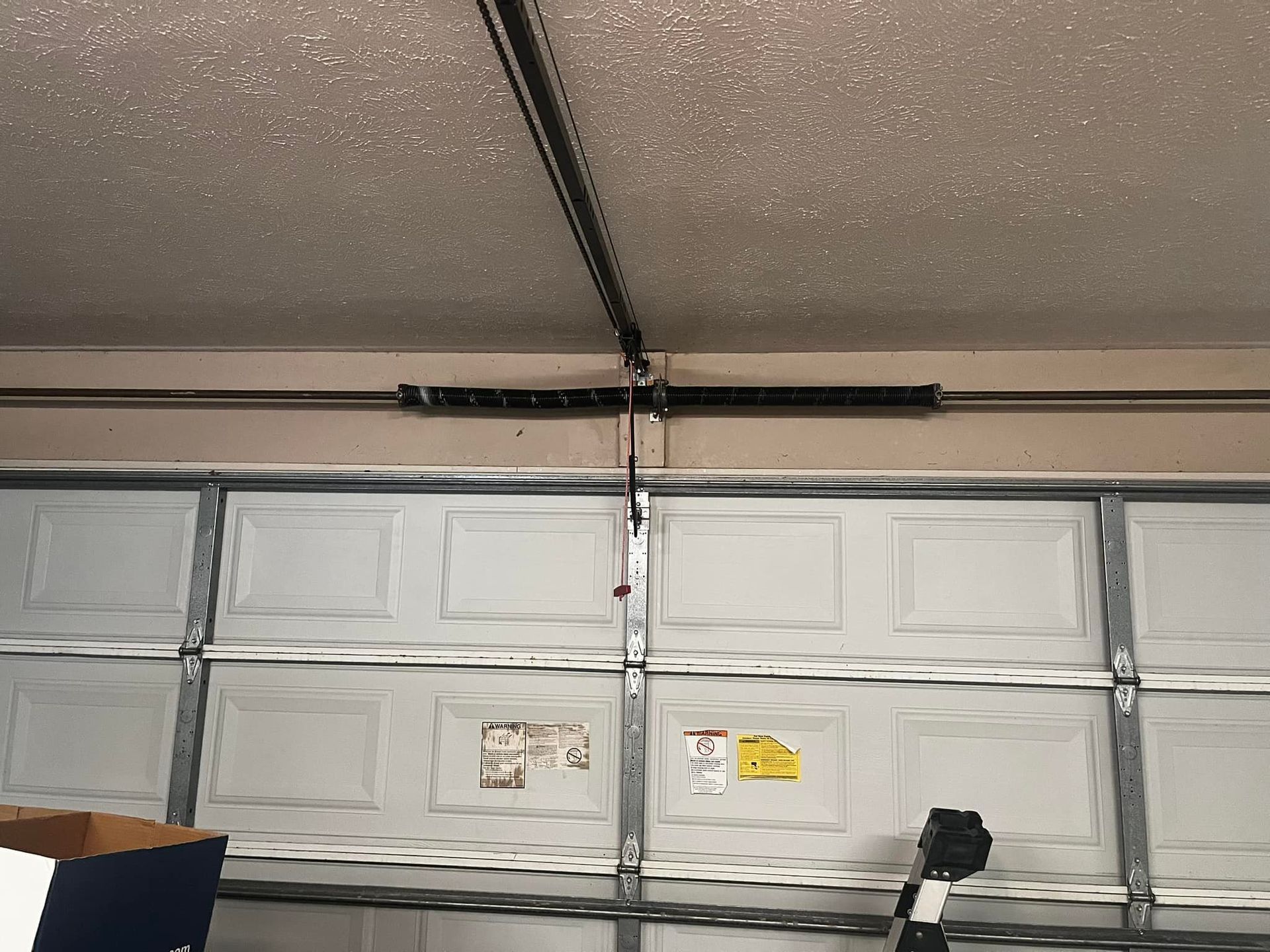 A garage door with a broken spring hanging from the ceiling.