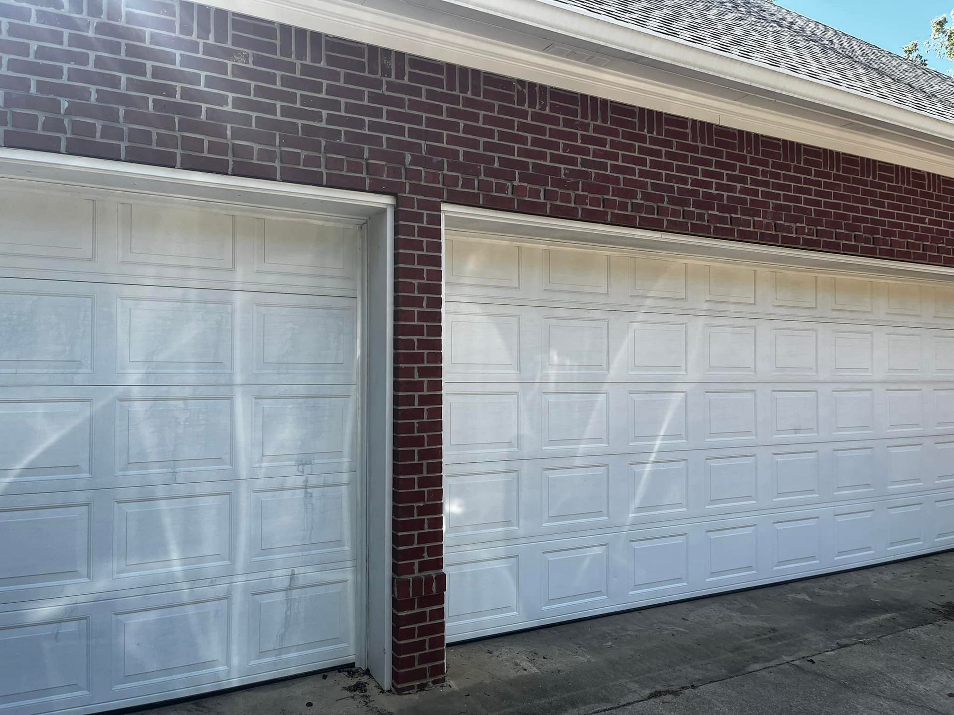 A couple of white garage doors on a brick building.