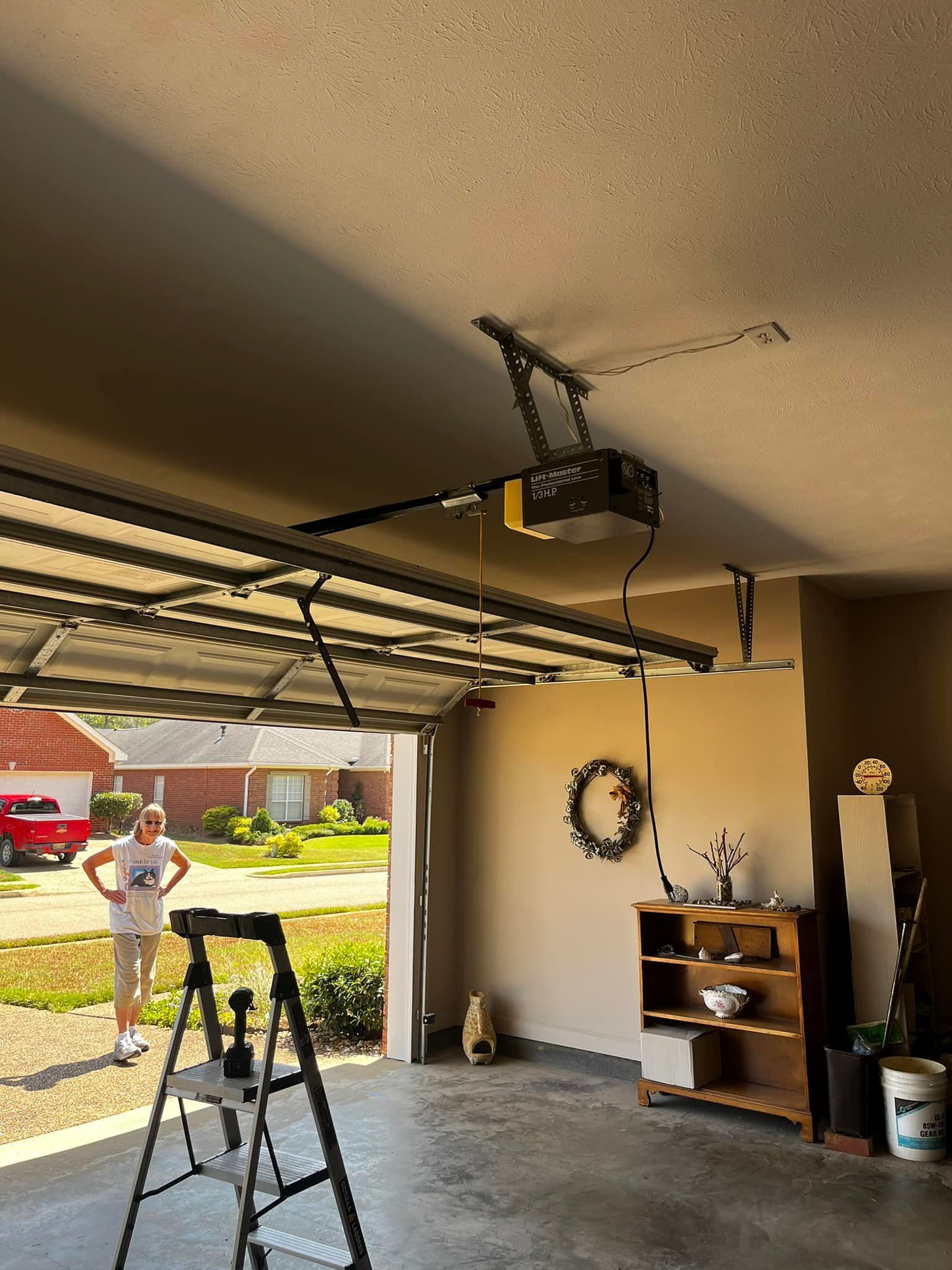 A man is standing in a garage with a garage door open.