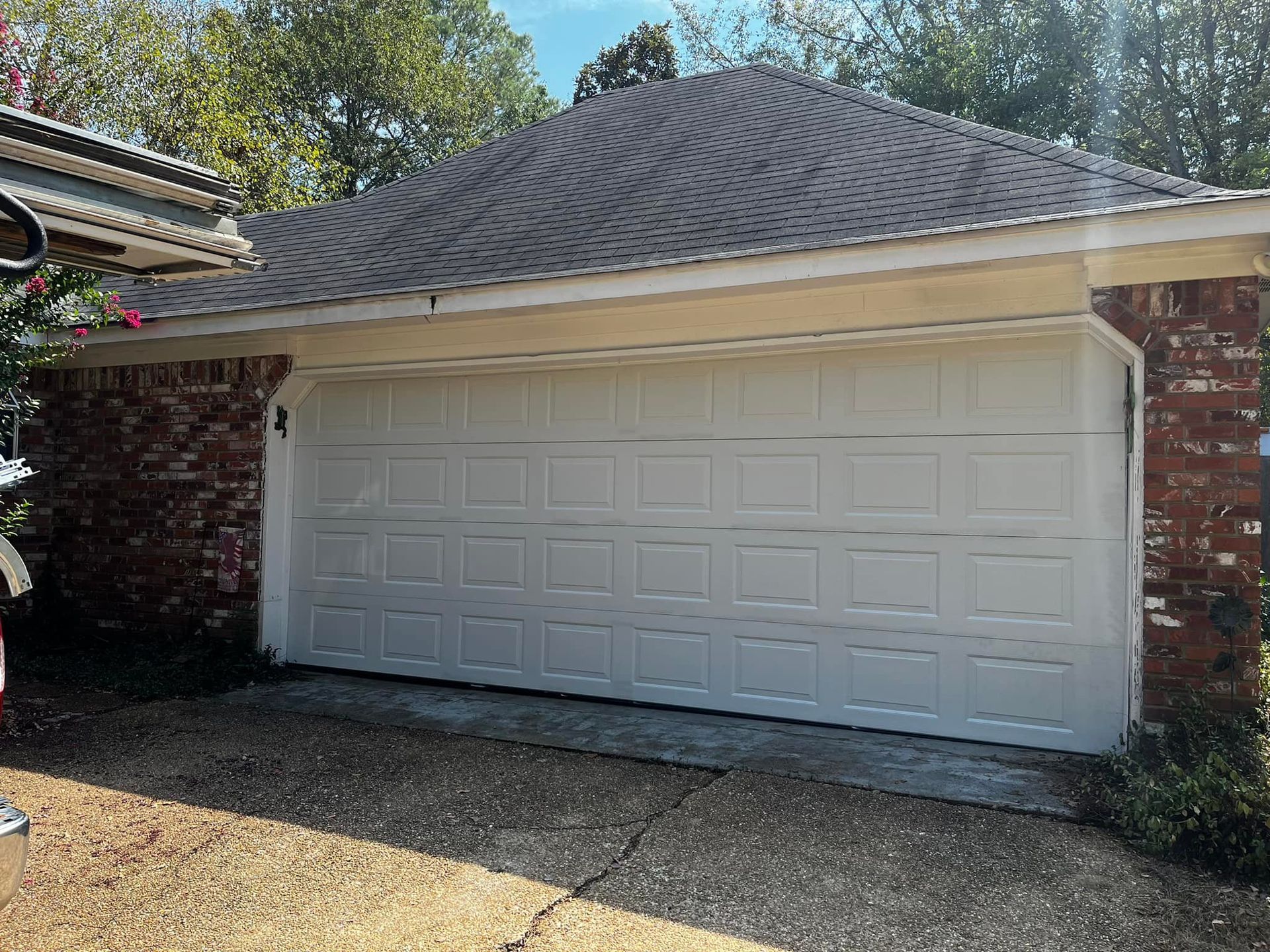 A white garage door is sitting in front of a brick house.