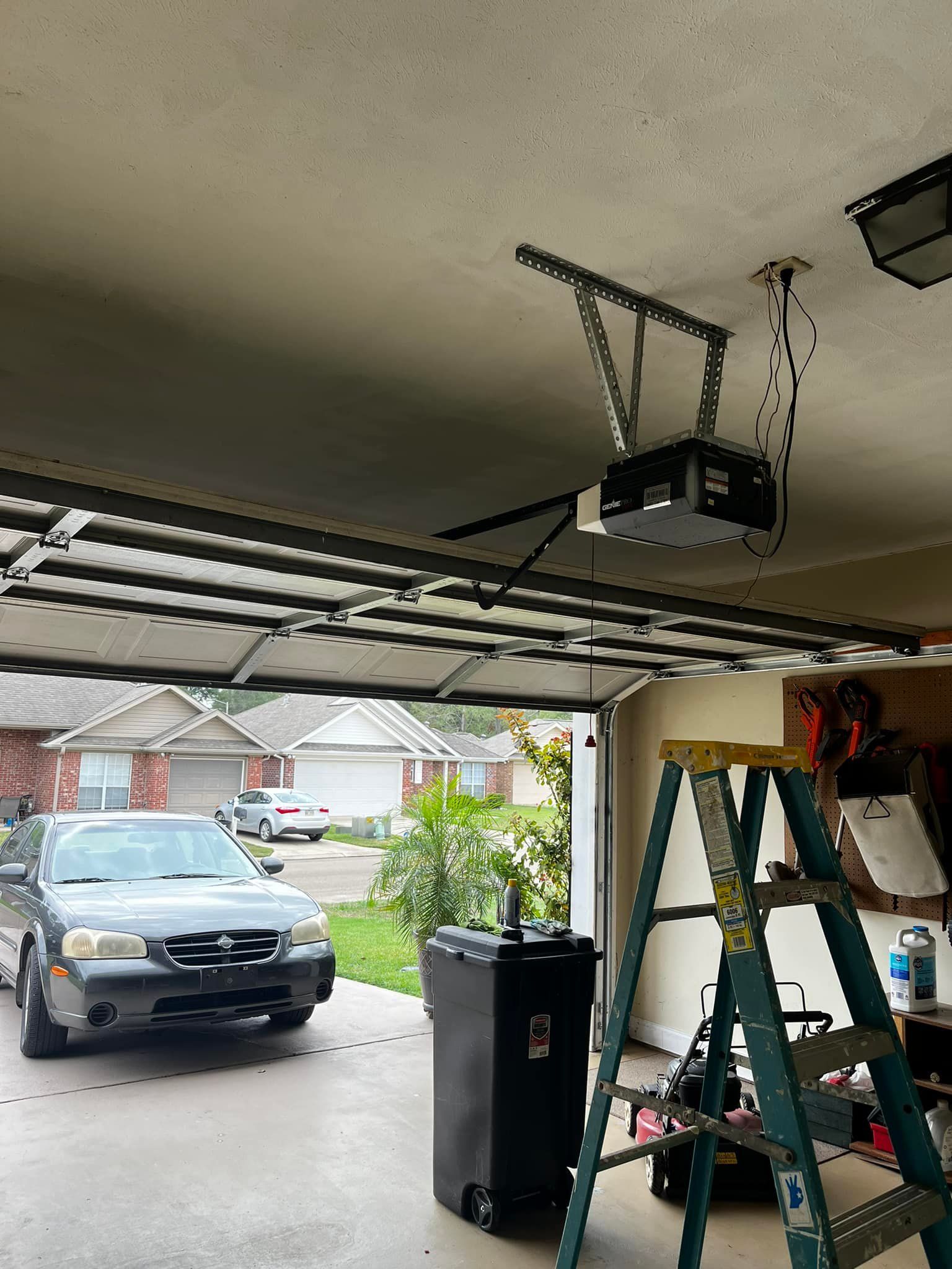 A car is parked in a garage next to a ladder.