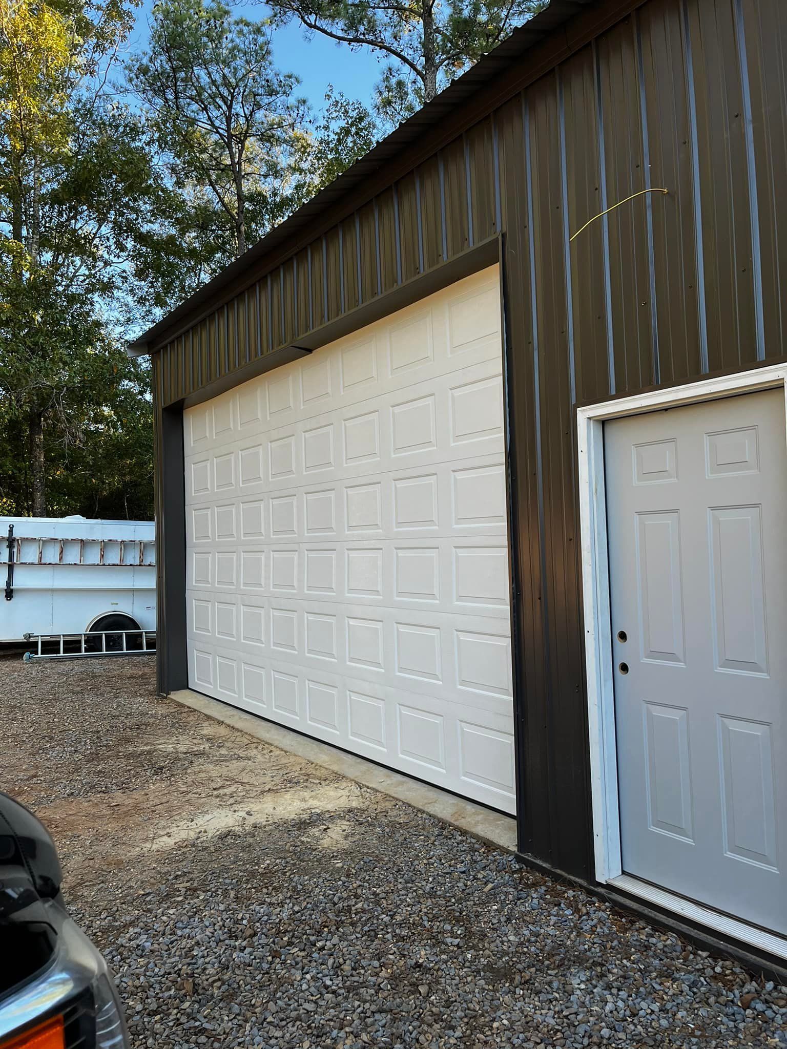 A car is parked in front of a garage with a large garage door.