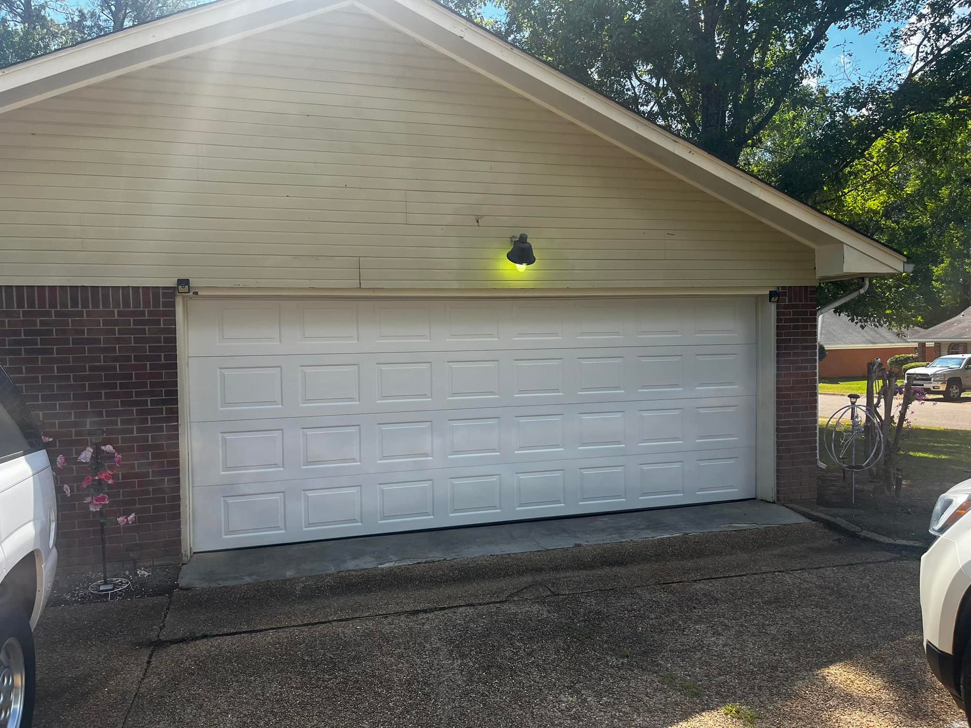 A white car is parked in front of a white garage door.
