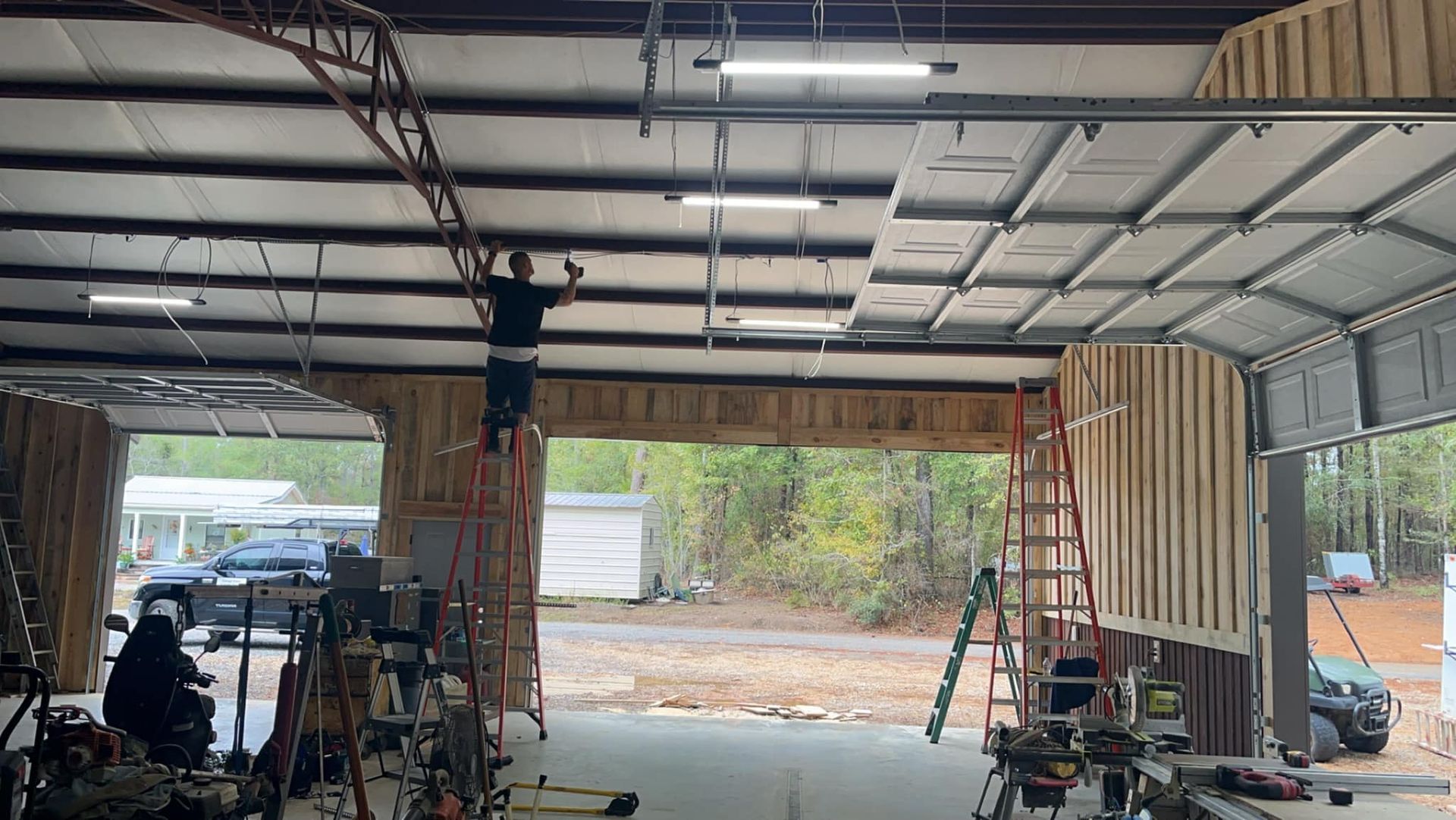 A man is standing on a ladder in a garage.
