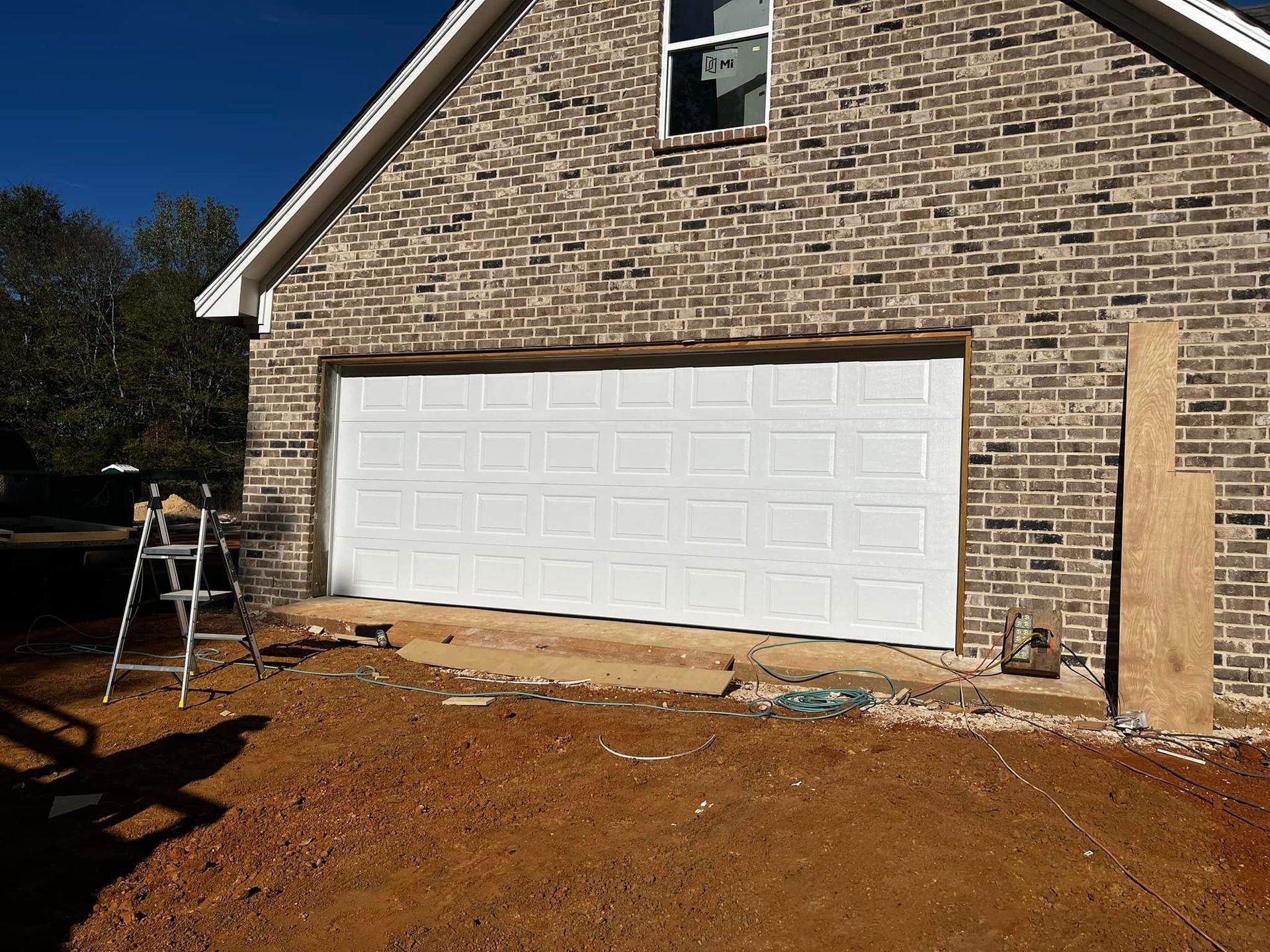 A white garage door is being installed on a brick building