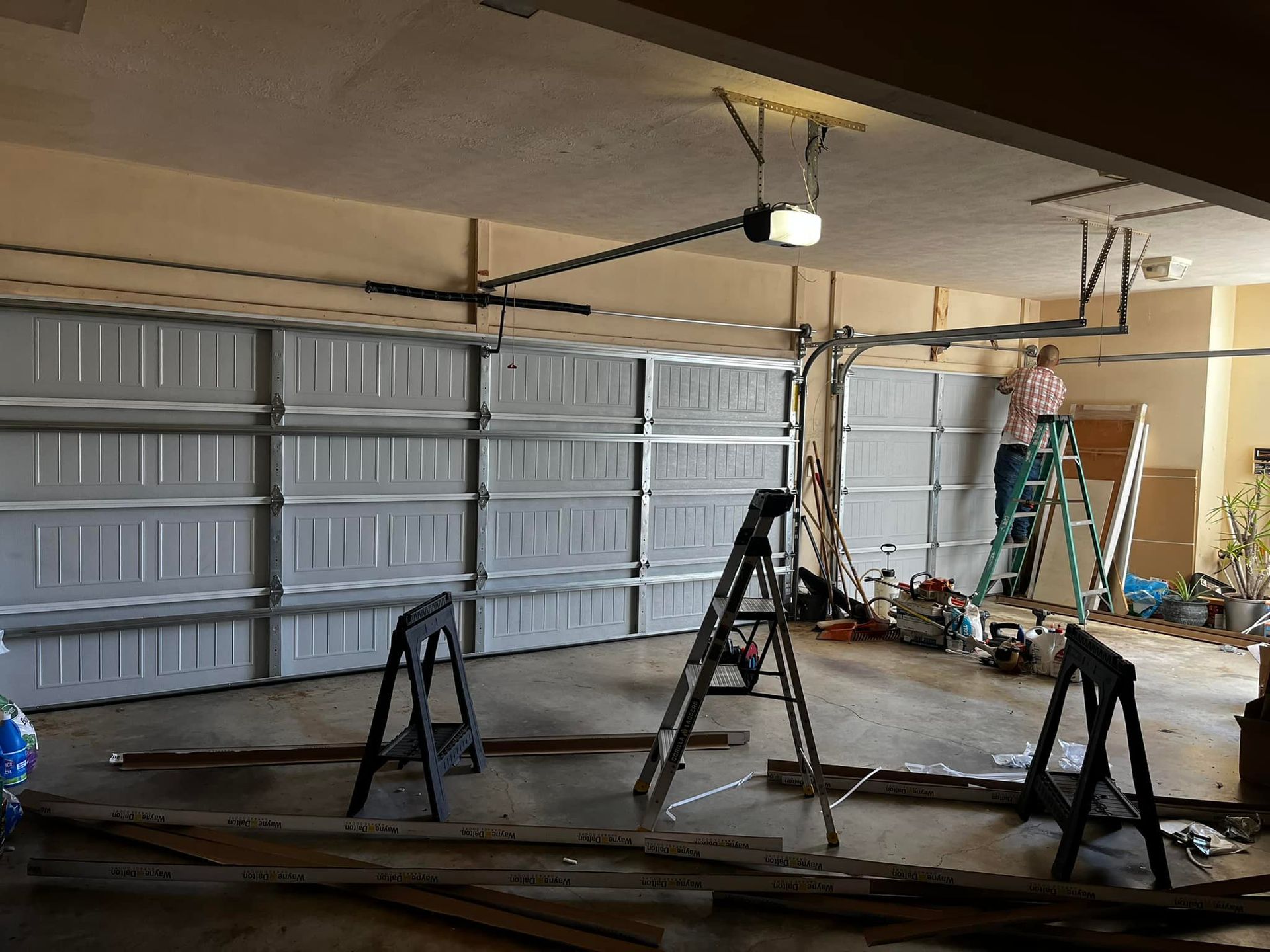 A man is working on a garage door with a ladder