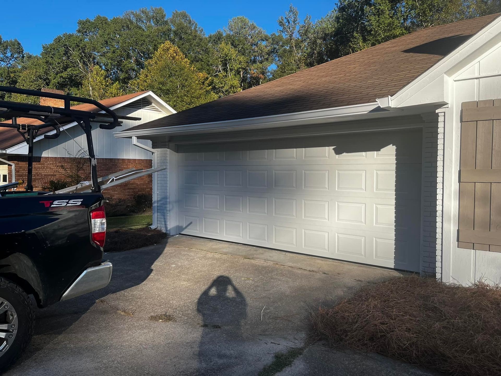 A black truck is parked in front of a white garage door.