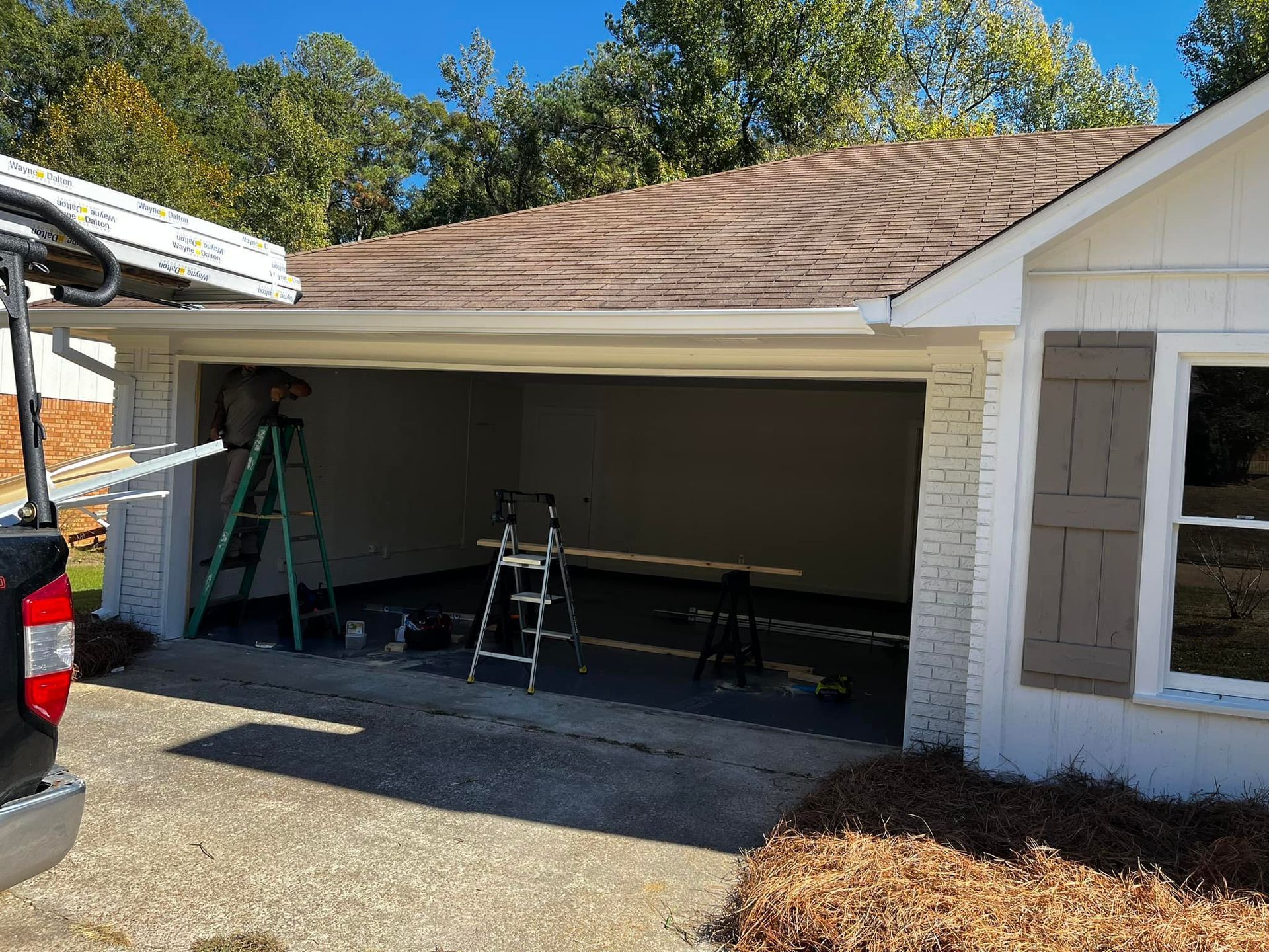 A truck is parked in front of a garage that is being remodeled.