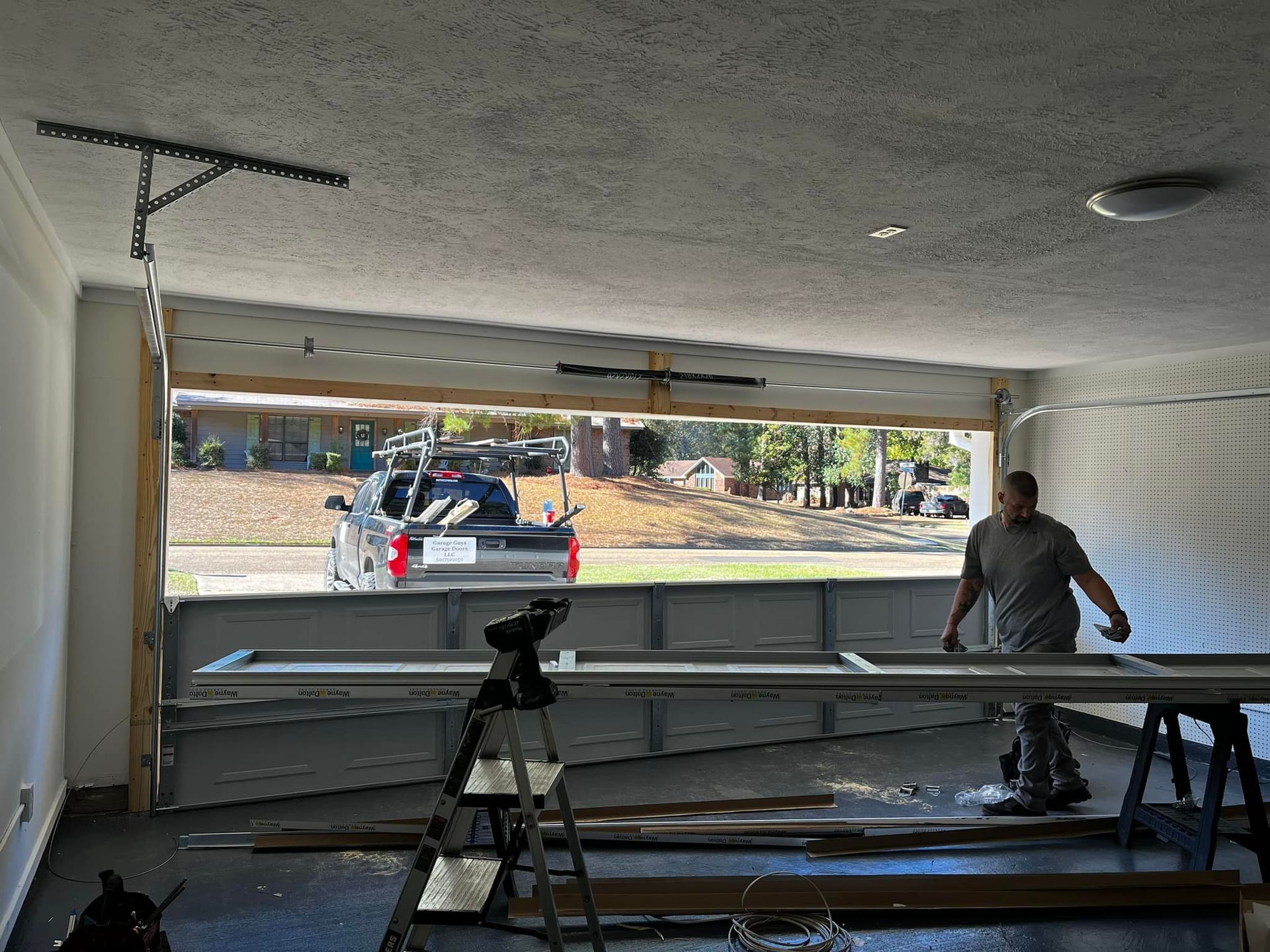 A man is working on a garage door in a garage.
