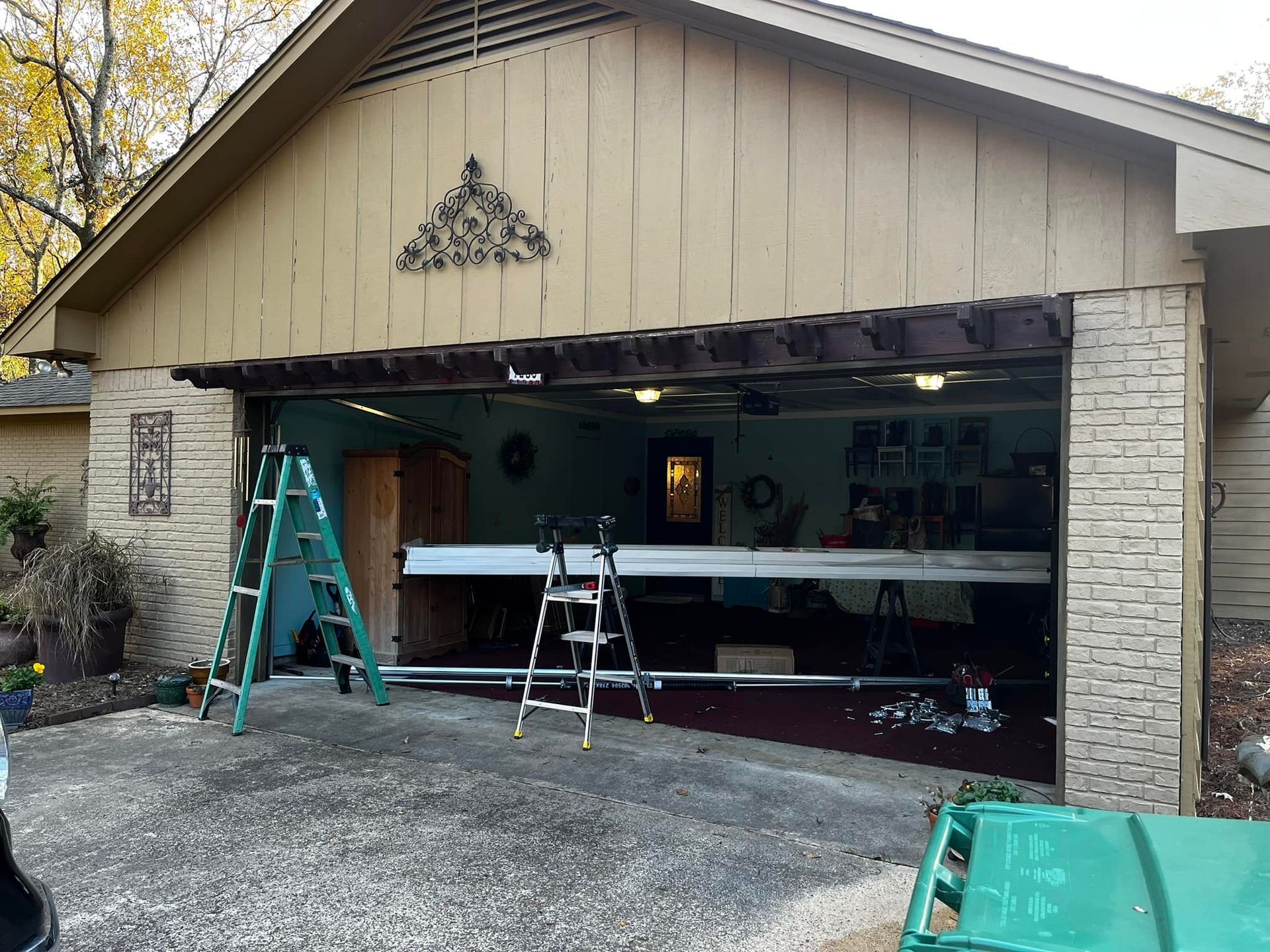 A garage door is being opened and a ladder is sitting in front of it.