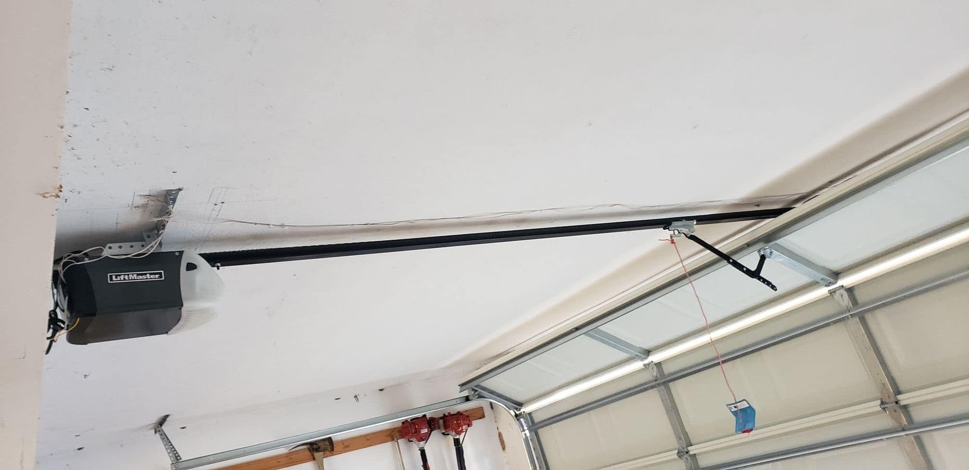 A garage door opener is hanging from the ceiling of a garage.