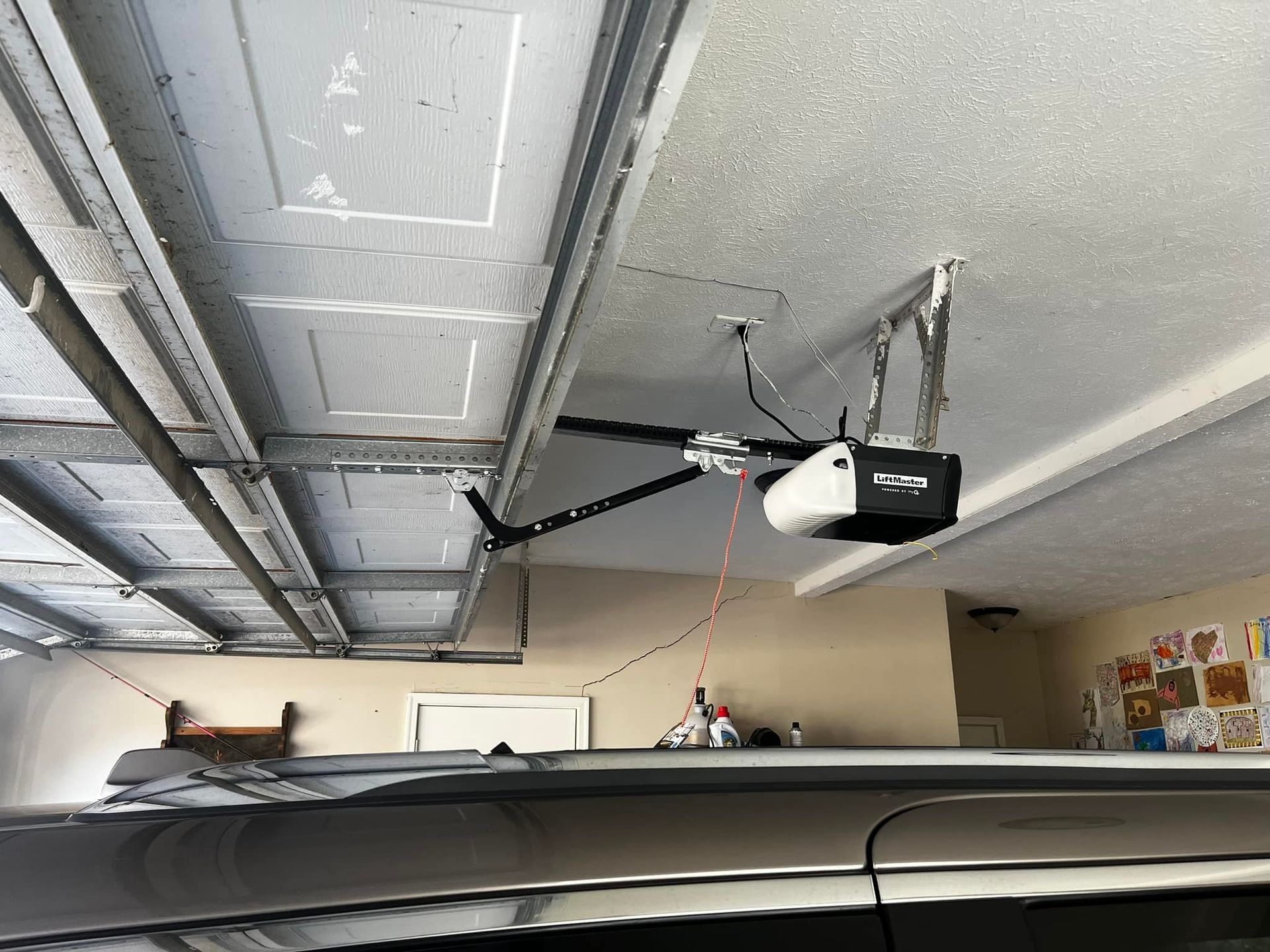 A garage door opener is hanging from the ceiling of a garage.