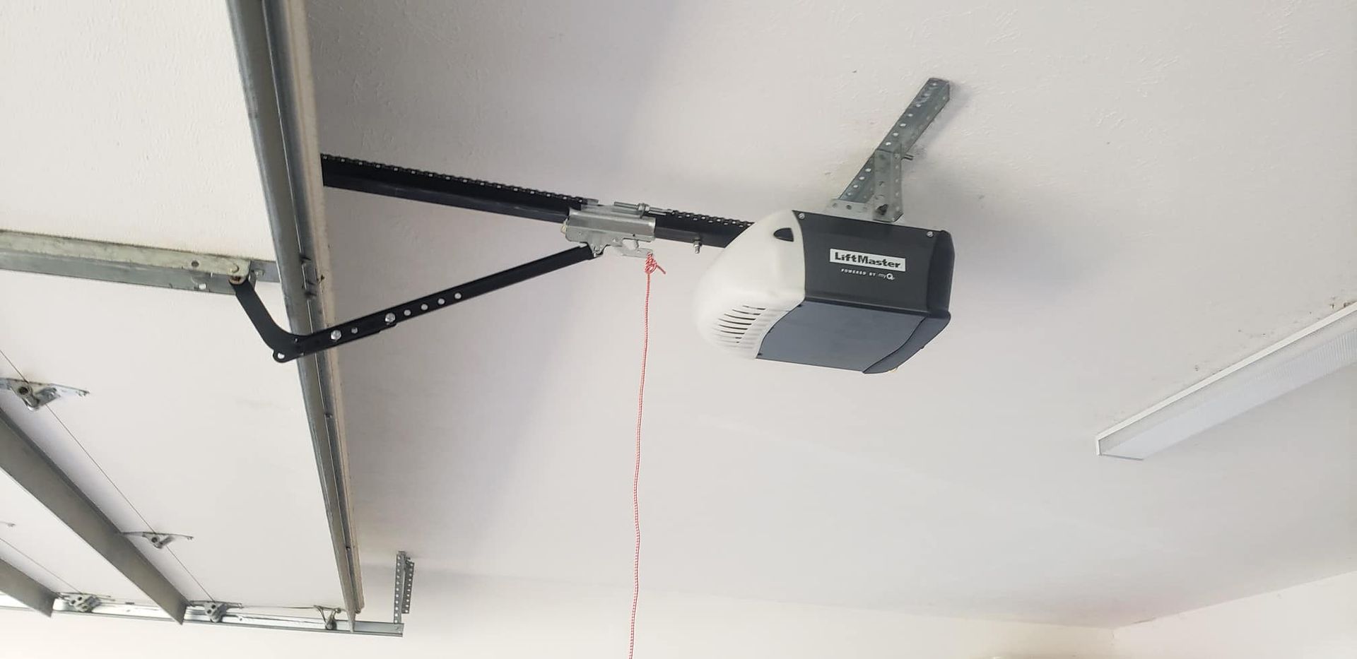 A garage door opener is hanging from the ceiling of a garage.