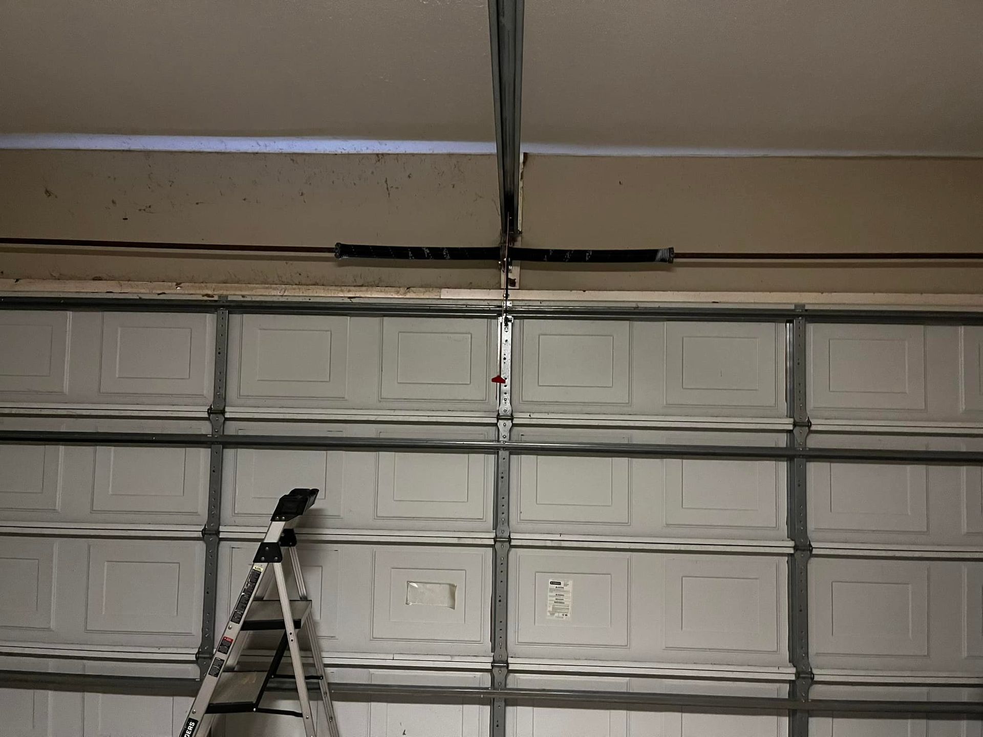 A ladder is sitting in front of a garage door