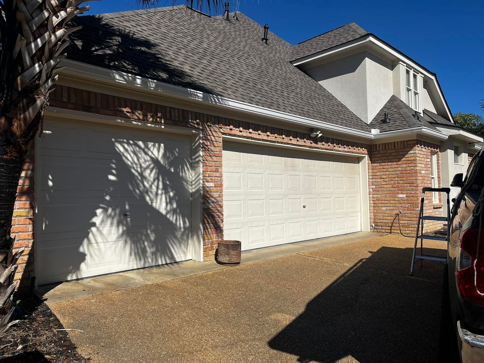 A truck is parked in front of a house with two garage doors.