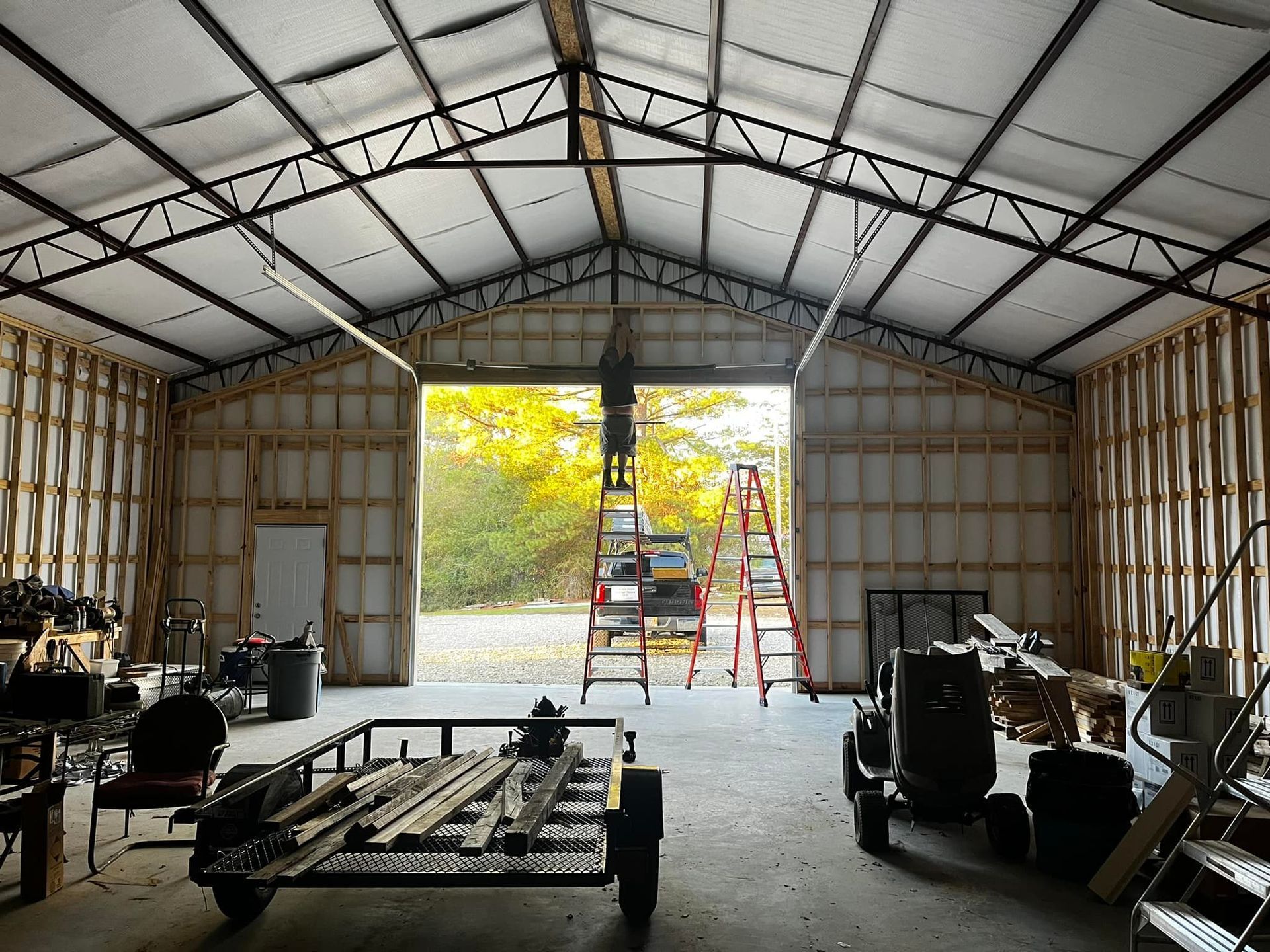 A man standing on a ladder in a garage with the door open