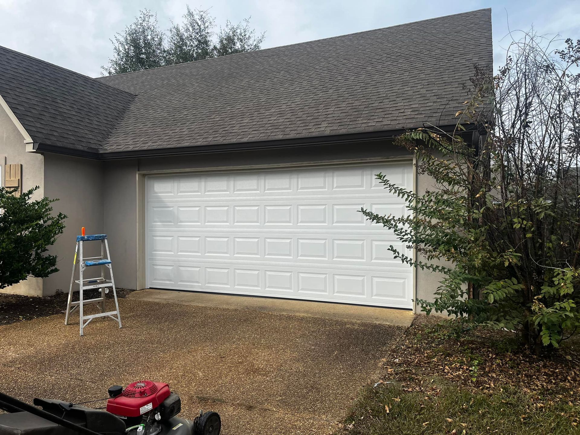 A lawn mower is parked in front of a garage door.