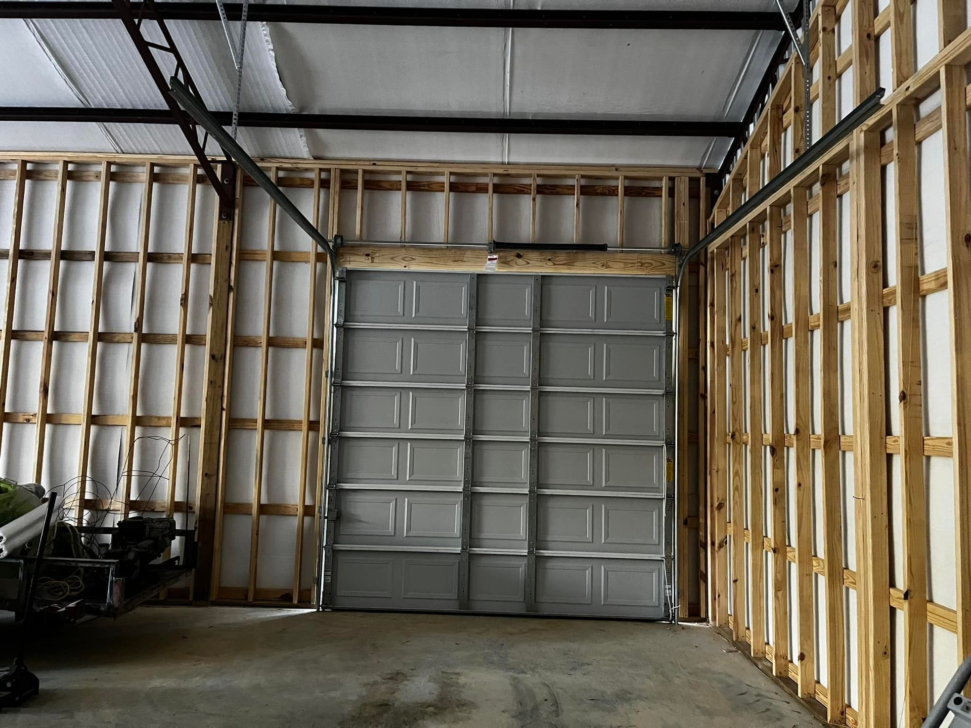 A garage with a gray garage door and wooden walls