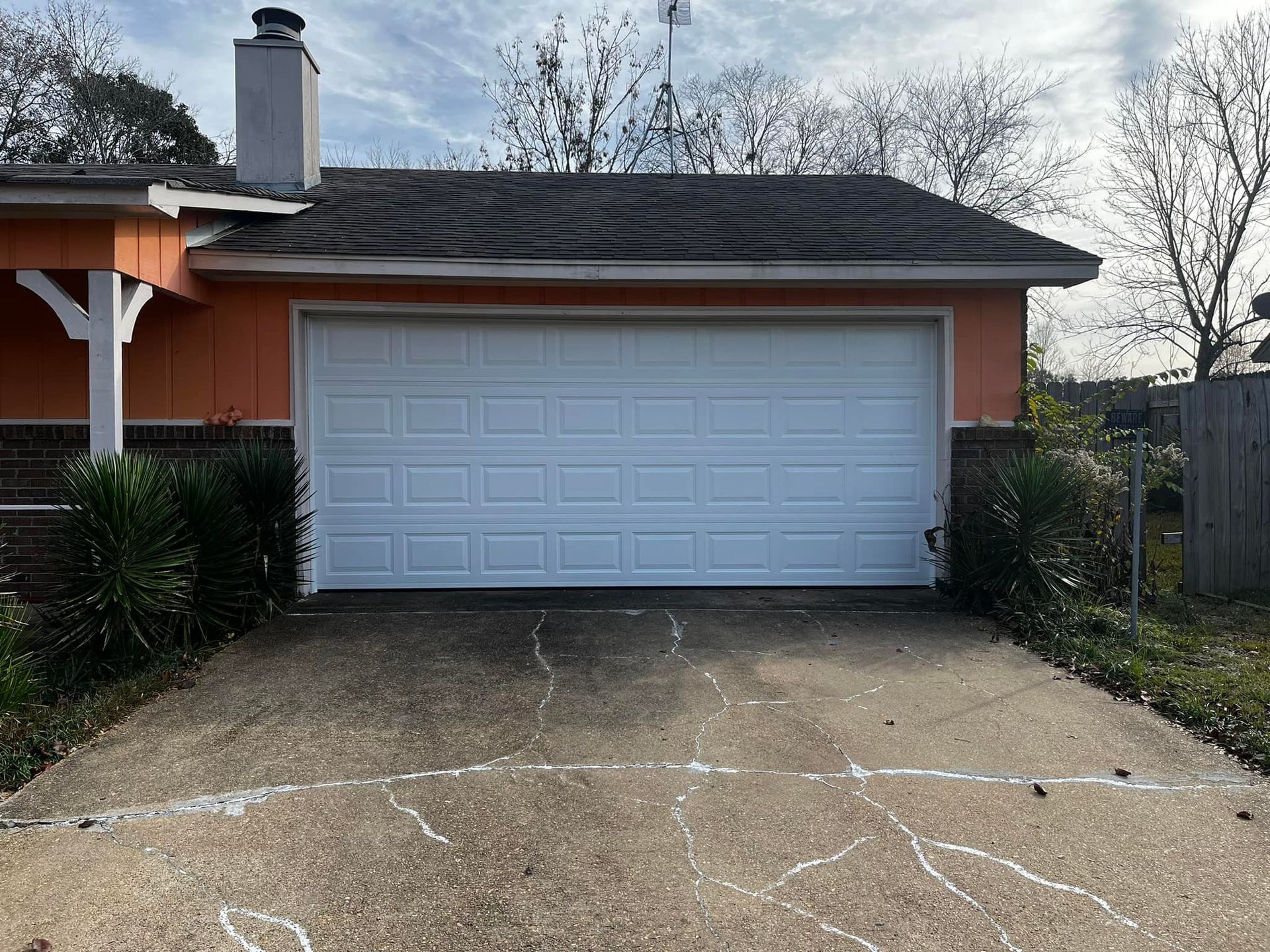 A white garage door is sitting in front of a house.