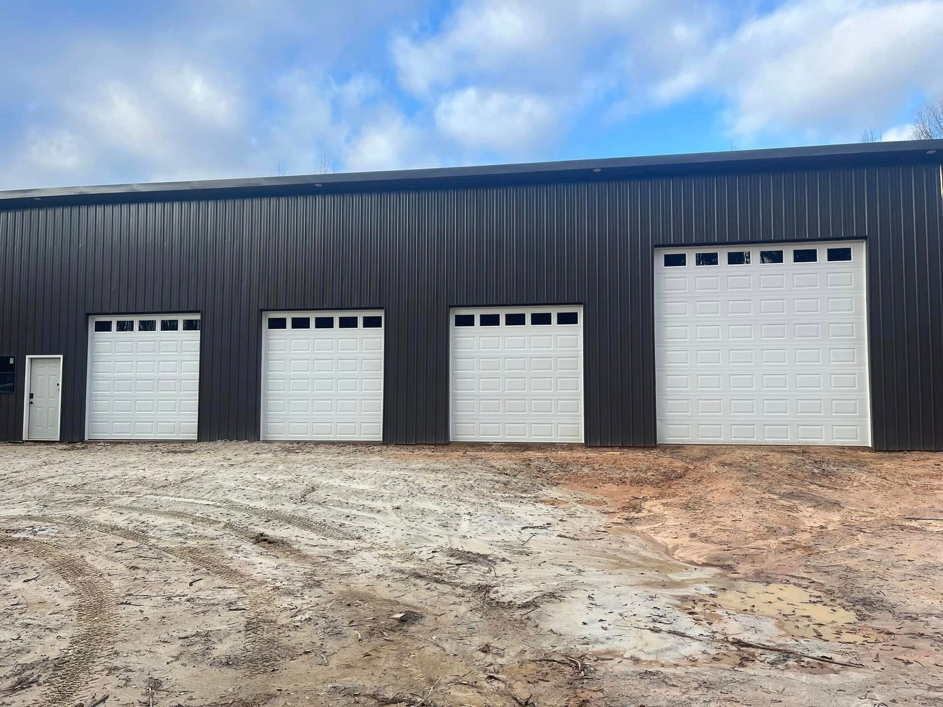 There are three garage doors on the side of a building.