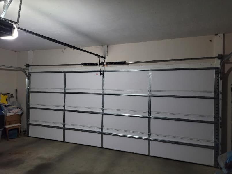 A white garage door is open in a garage.