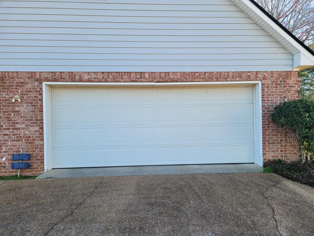 A white garage door is sitting in front of a brick house.