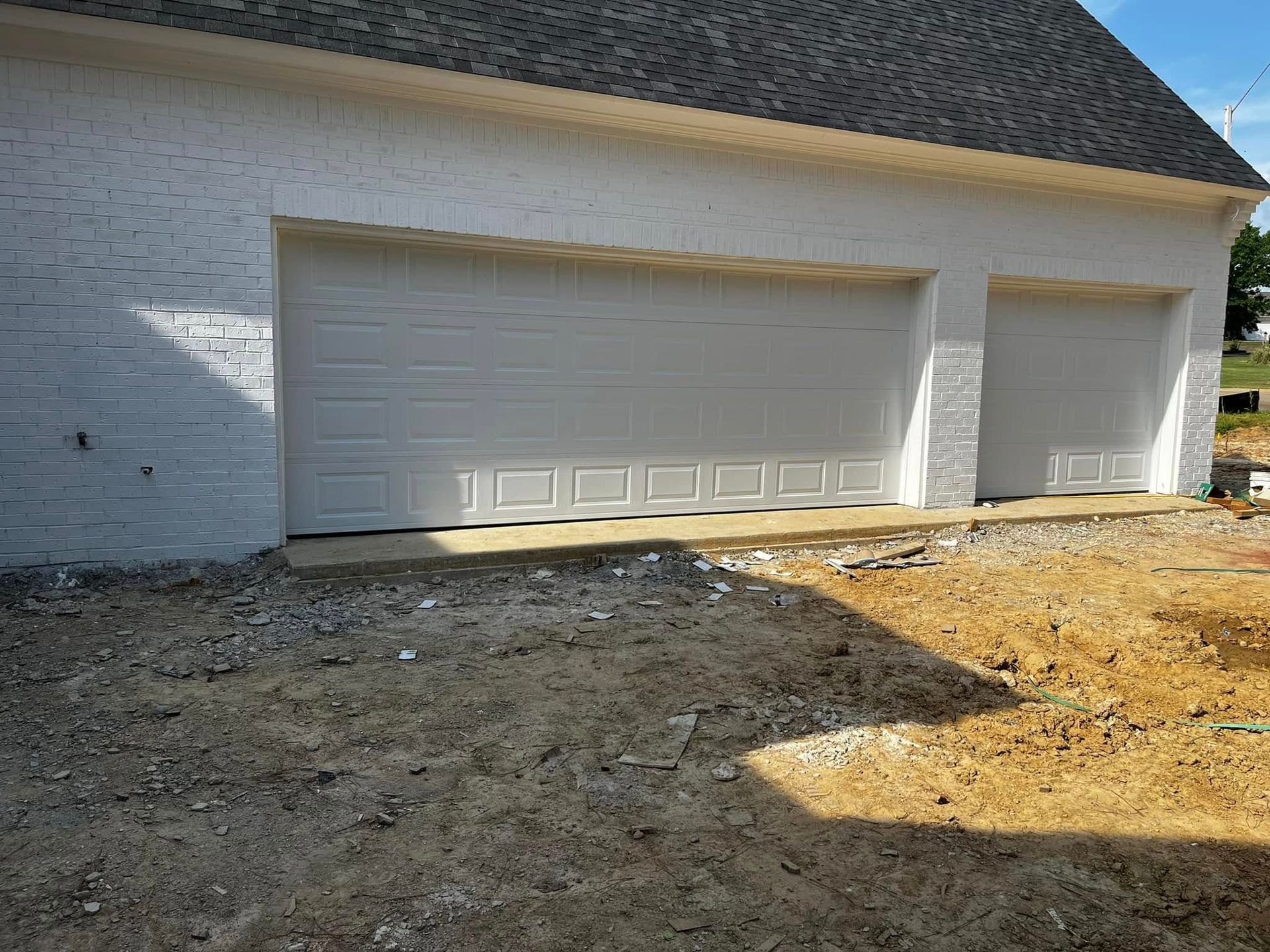 A white garage door is sitting in front of a brick building.
