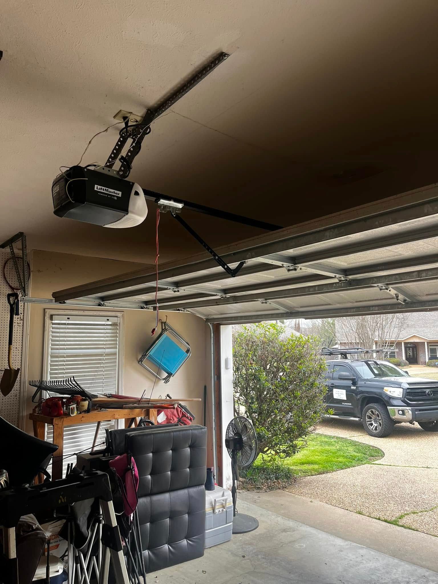 A garage with a ceiling fan and a car parked in the driveway.