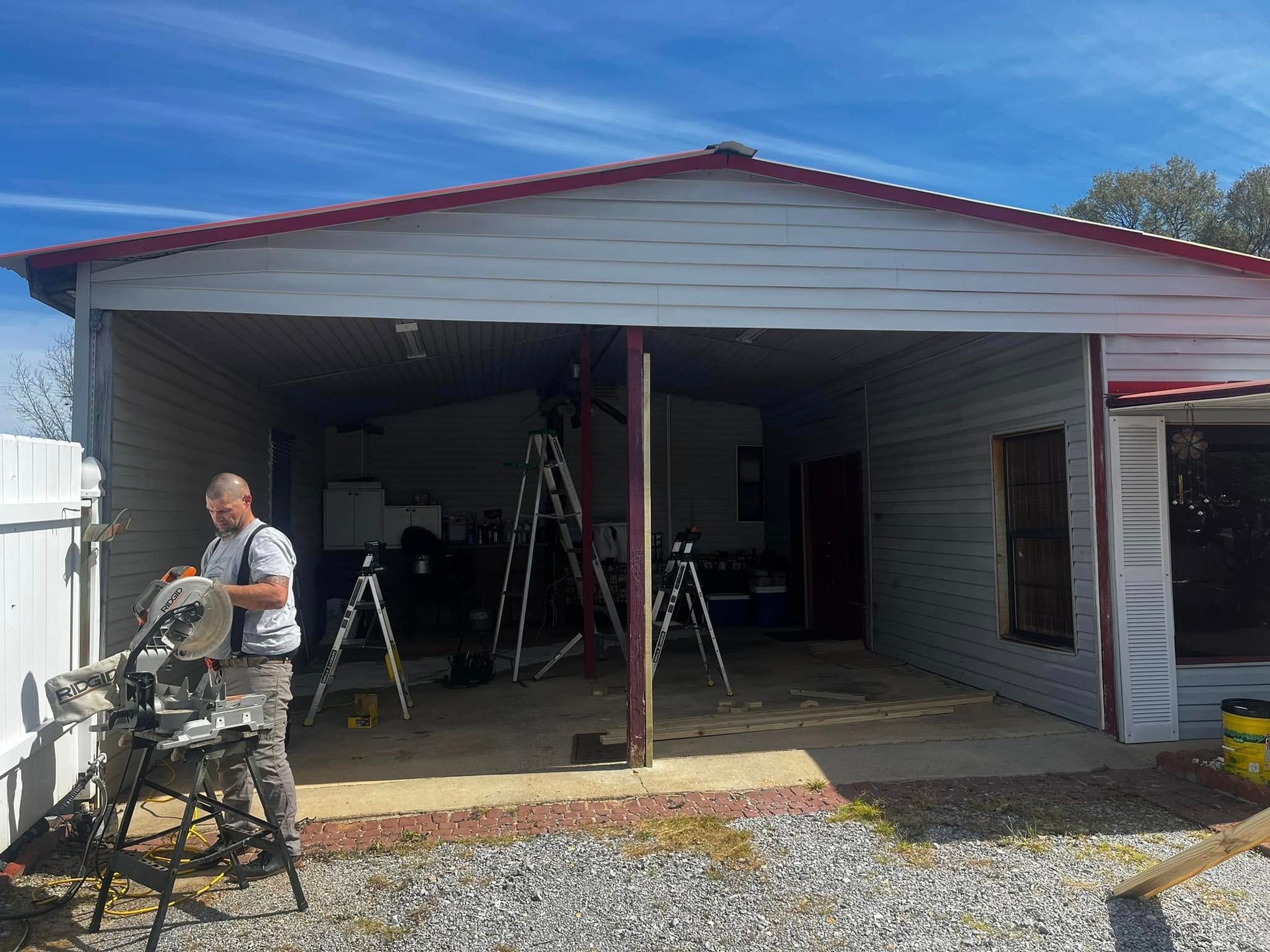 A man is standing in front of a house with a circular saw.