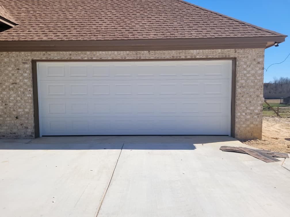 A white garage door is sitting in front of a brick house.