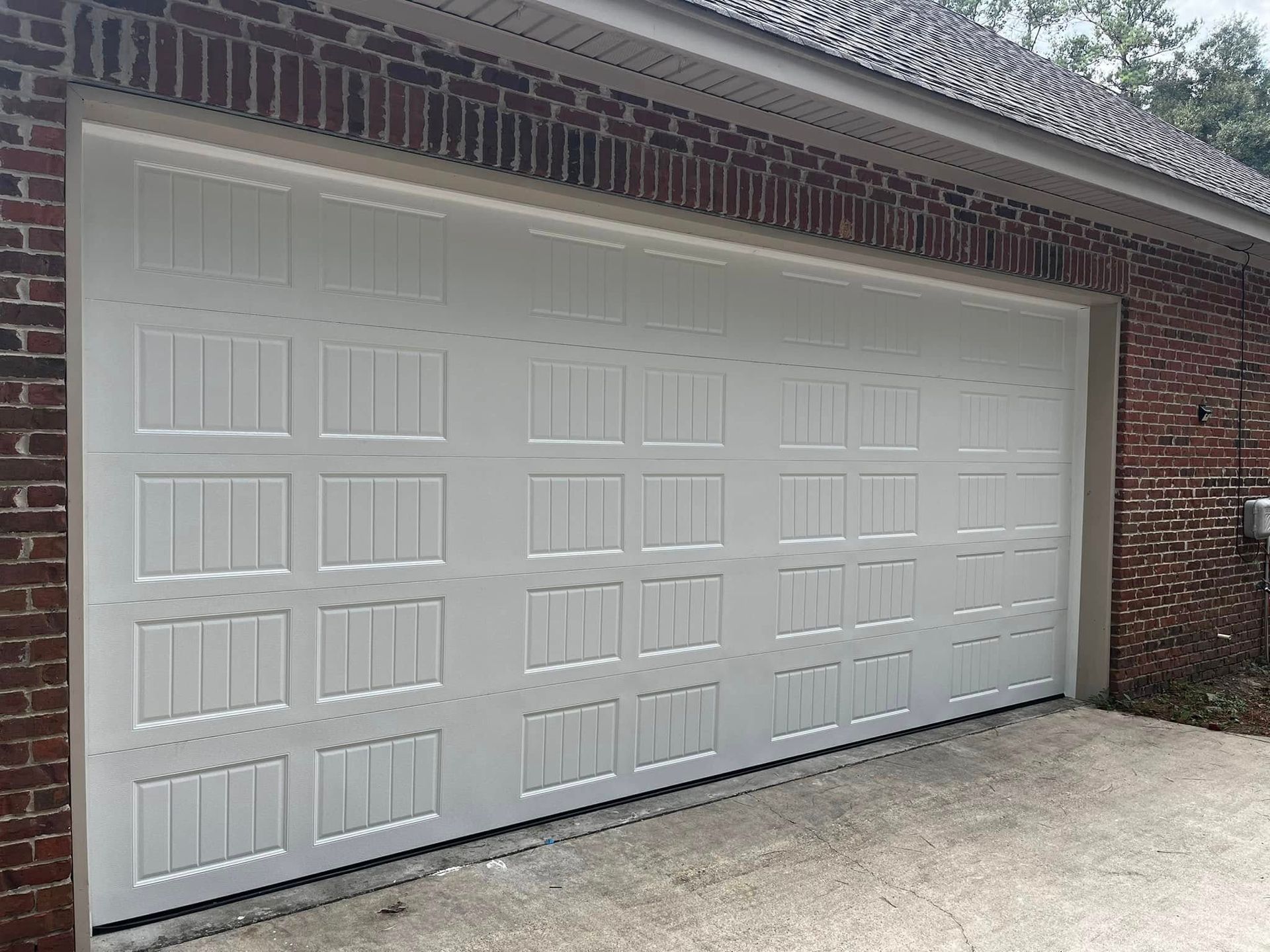 A white garage door is open on a brick building.